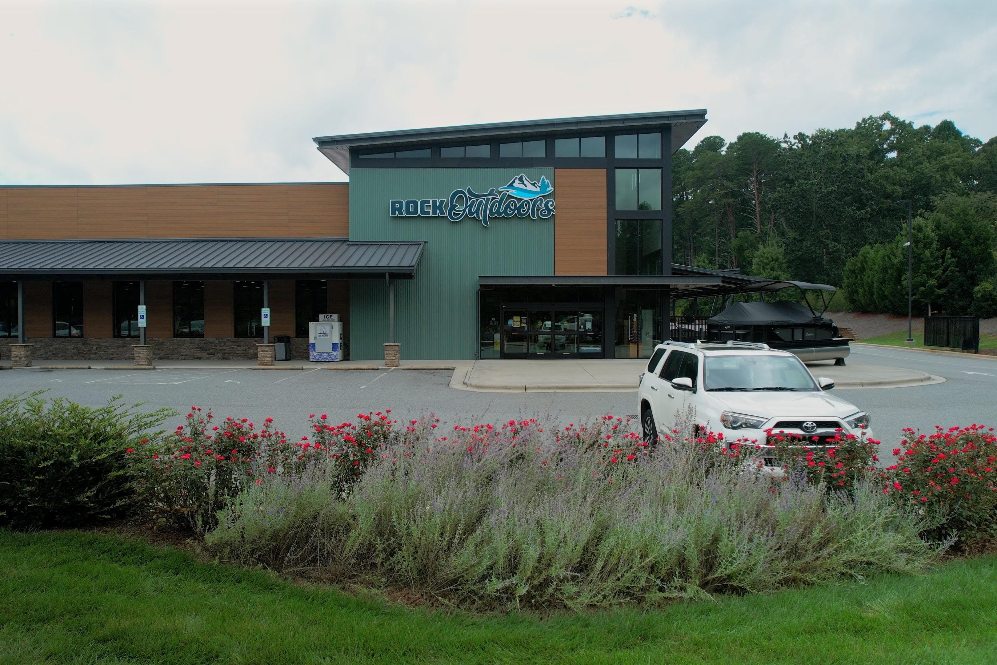 Outdoor store with a 2026 Barletta 23U boat and a white SUV in the parking lot.