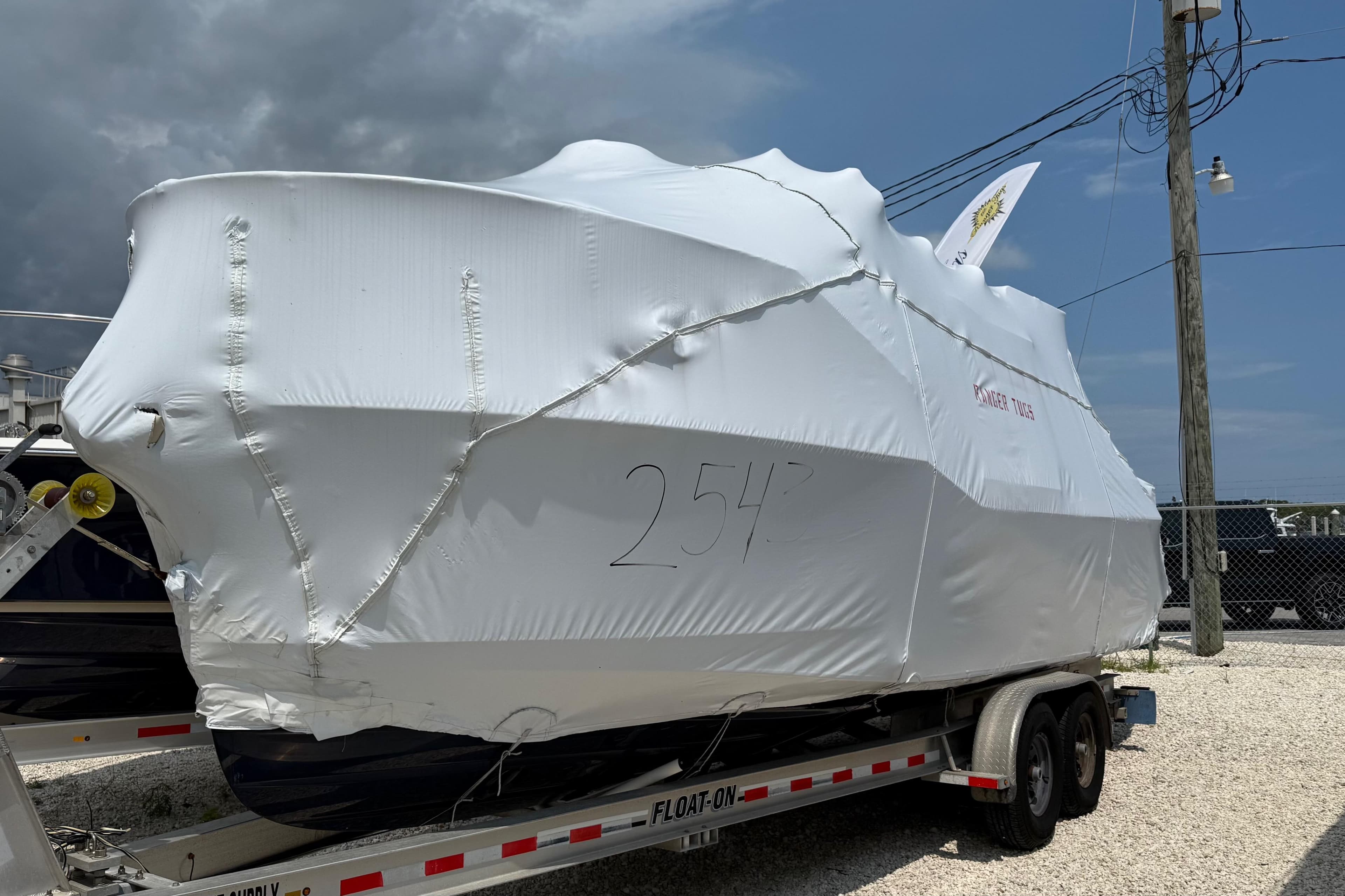 2025 Ranger Tugs R-25 boat covered in protective wrap on a trailer.