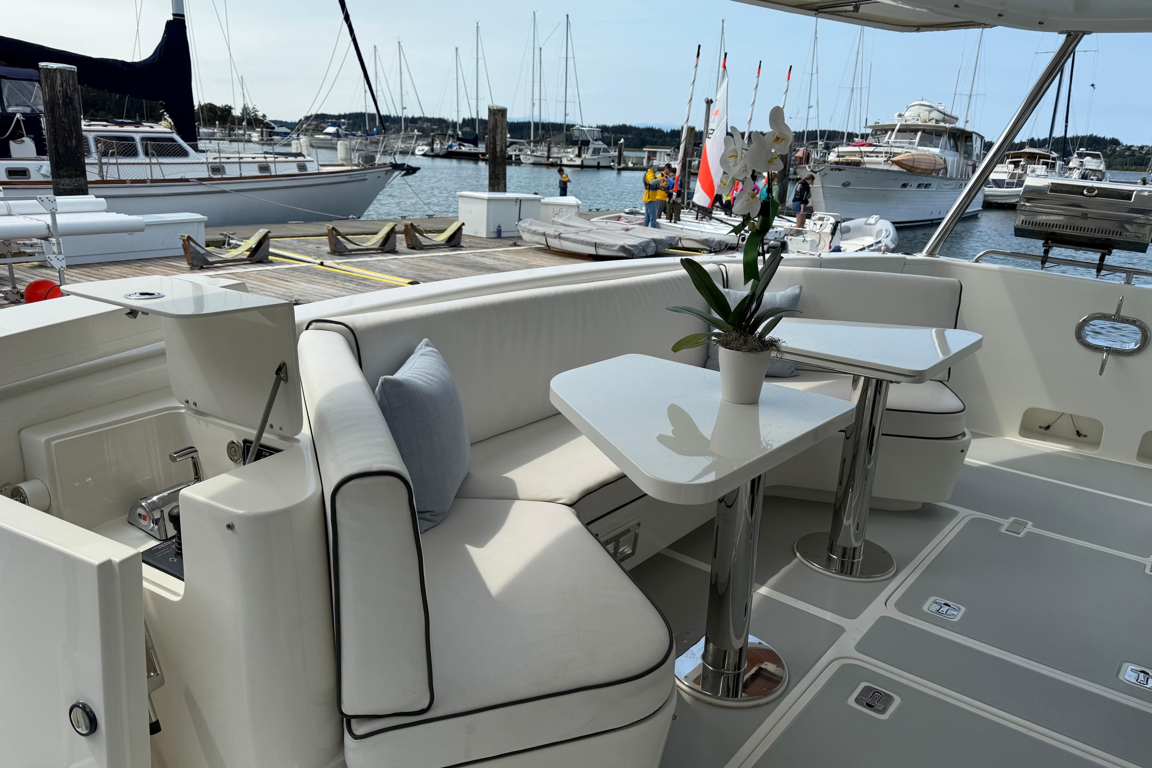 Luxurious 2009 Nordhavn N64 yacht deck with seating and table, docked at marina.