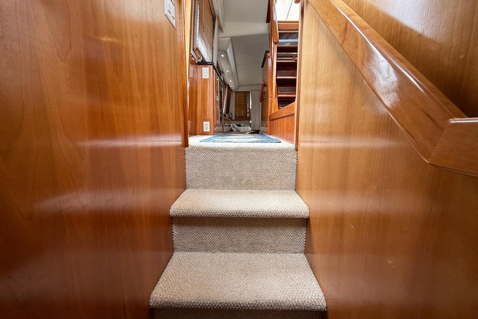 Carpeted stairs inside 2004 Navigator 4800 yacht with wooden paneling.
