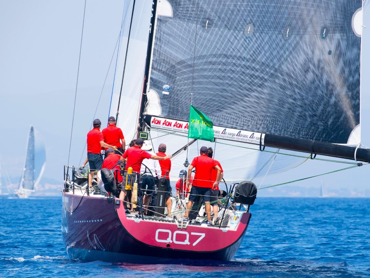 Sailboat Goetz Farr 53 Custom 2003 with crew in red shirts racing on blue ocean.