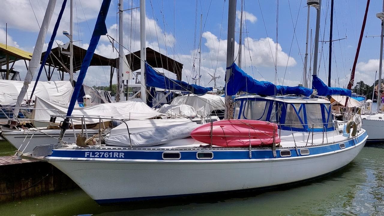 1981 Morgan Out Island 41 sailboat docked, featuring blue covers and a red kayak on deck.