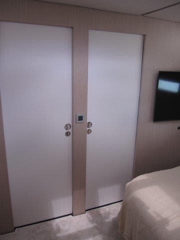 2024 Jeanneau 55 yacht interior with dual white doors and wall-mounted TV.
