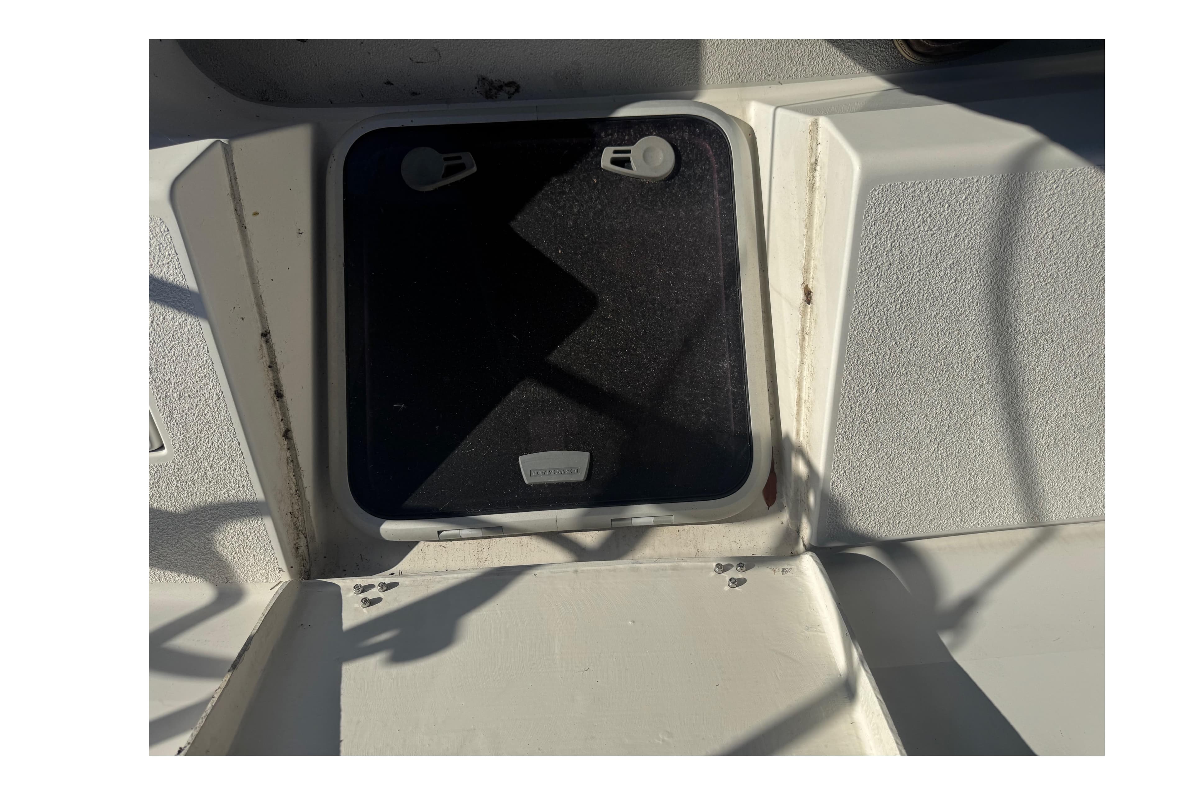 Hatch on a 2006 Catalina 309 sailboat deck, showing wear and shadows.
