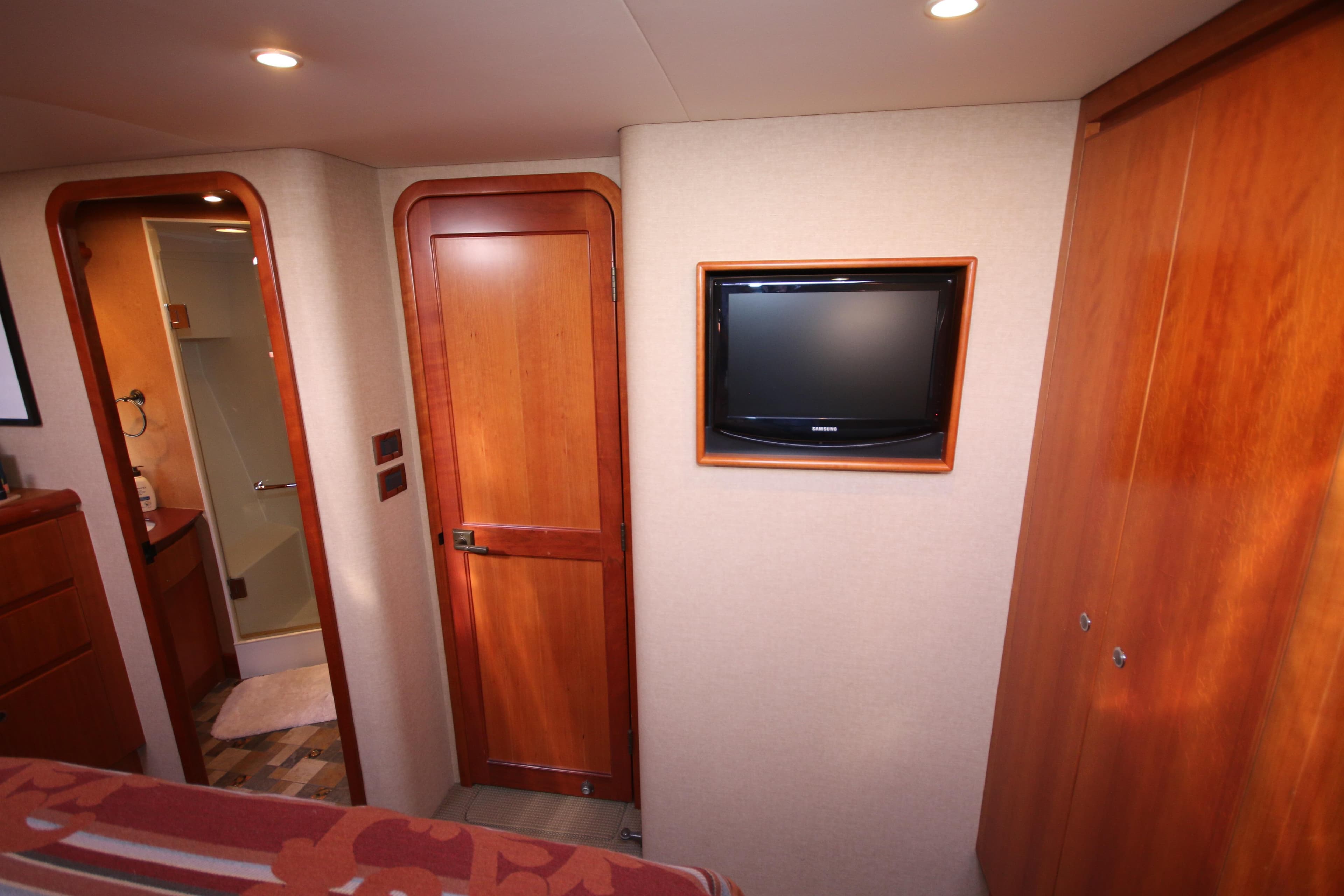 Luxurious 2004 West Bay 68 Sonship Pilothouse interior with TV and wooden accents.