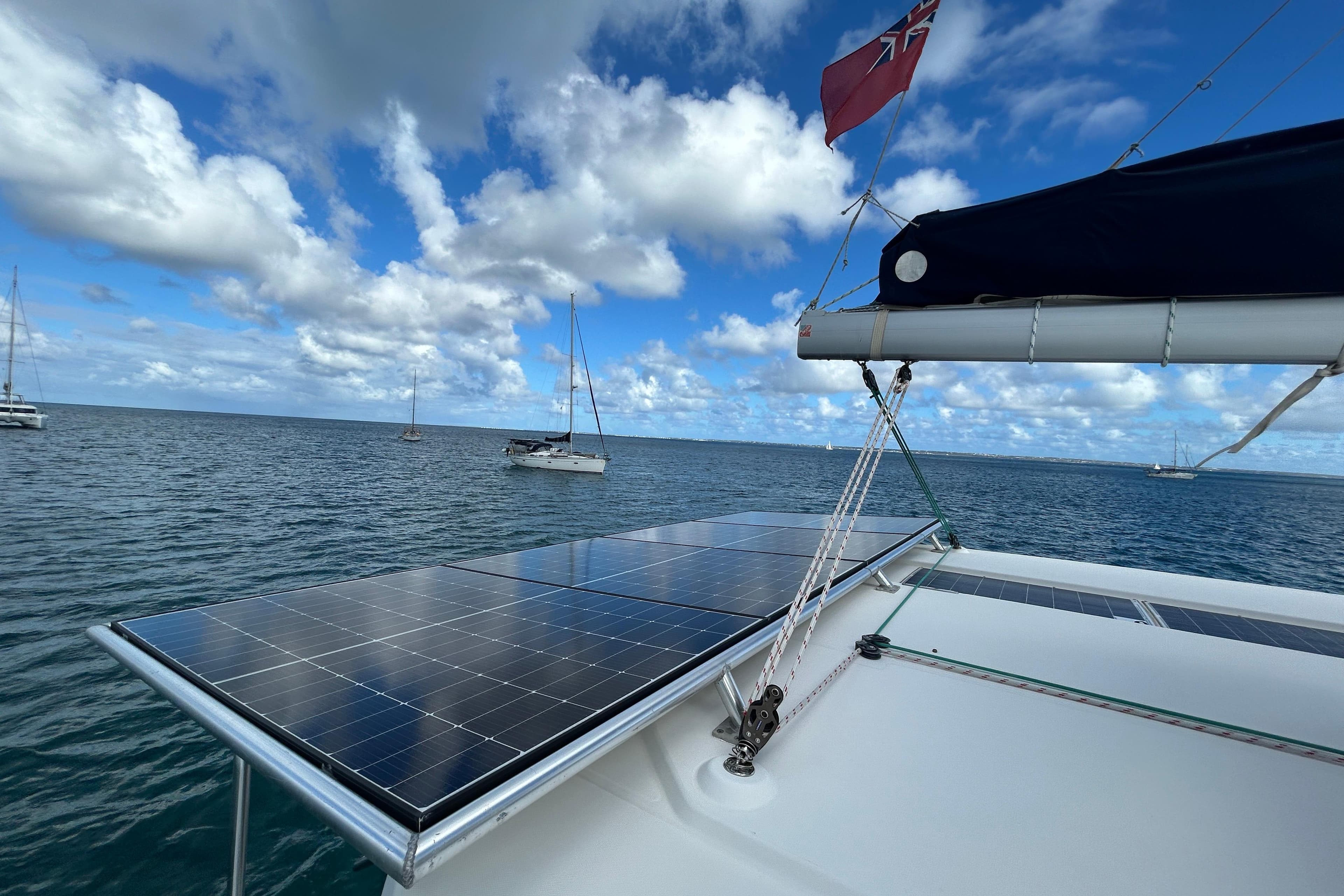 Catamaran with solar panels on deck, Leopard 45 model, sailing under a cloudy sky.