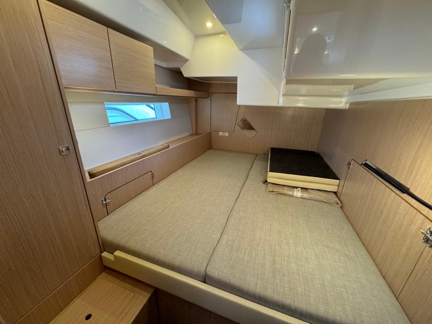 2024 Bavaria C50 yacht cabin with modern wood finish and cozy bedding.