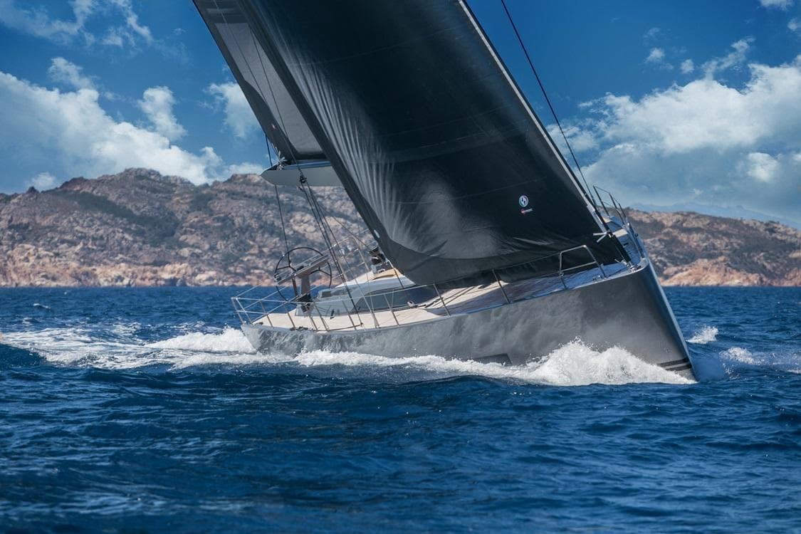 Sleek 2026 Solaris 64RS yacht sailing in open sea with mountainous backdrop.