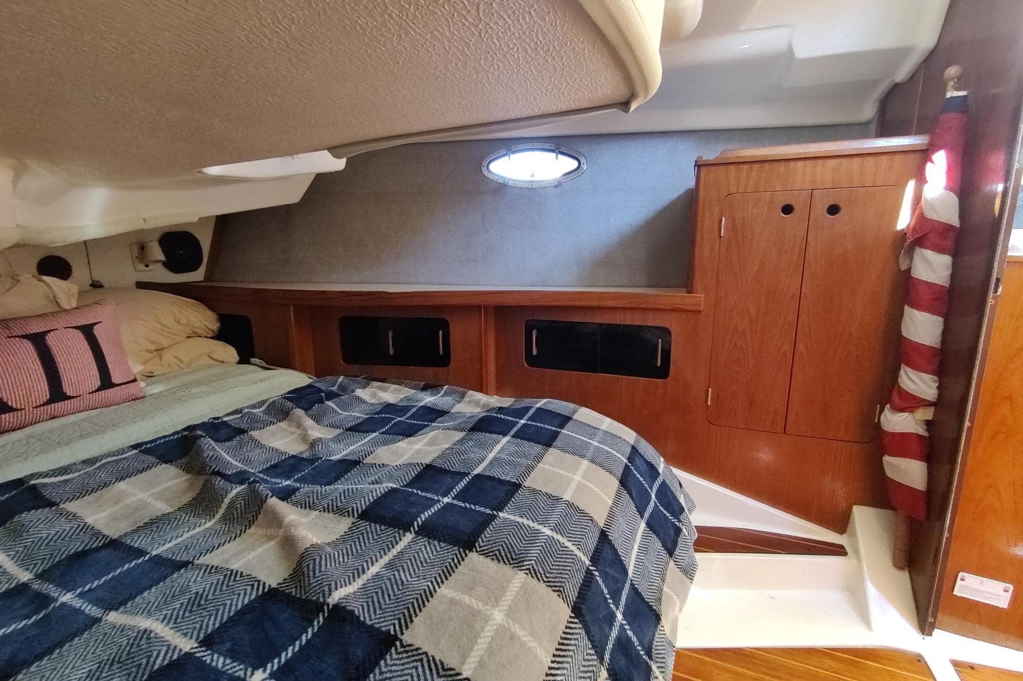 Cozy cabin interior of 1987 Hunter 37 Legend sailboat with plaid bedding and wooden cabinetry.