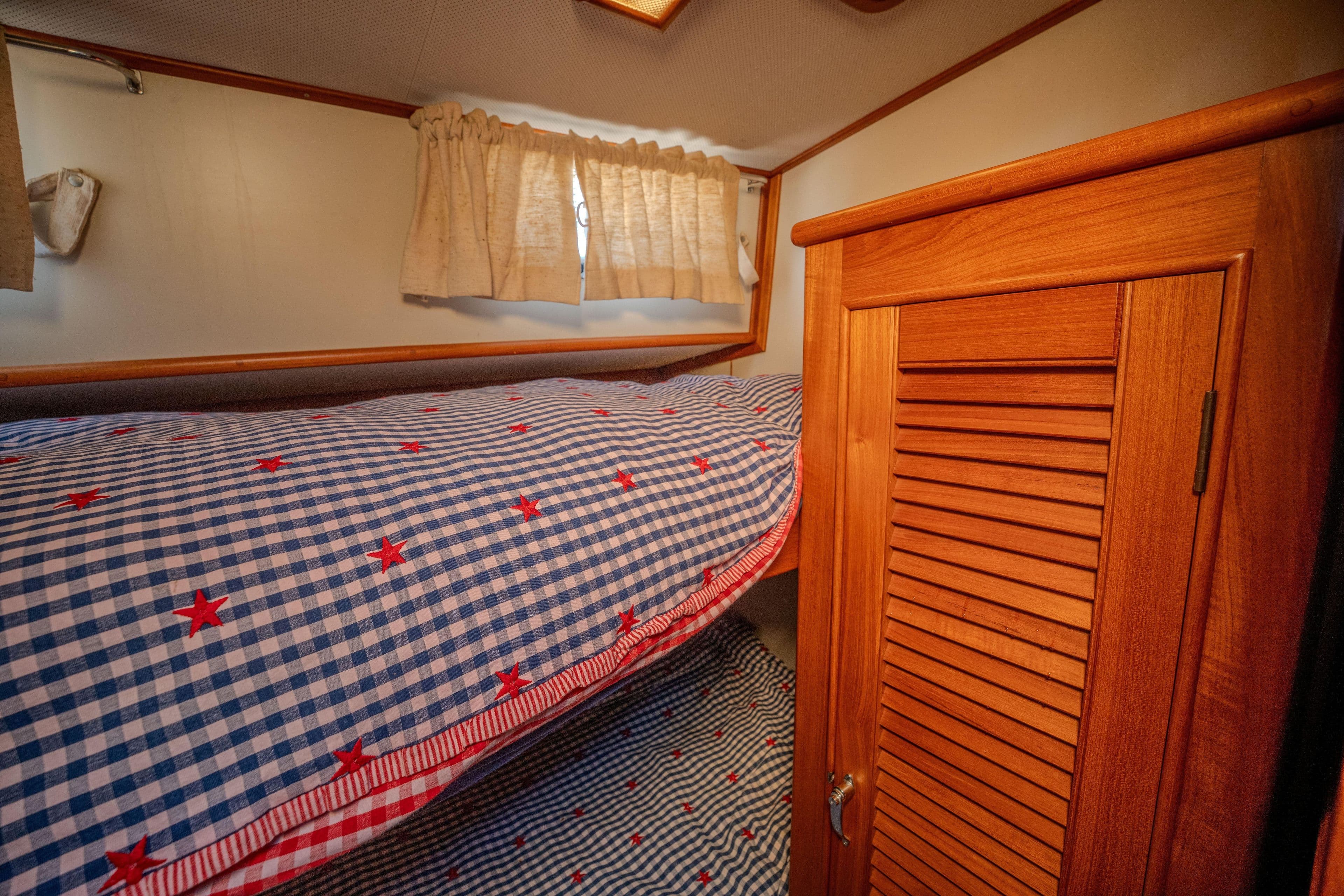 Cozy cabin interior of 1998 Grand Banks 43 Eastbay EX with checkered bedding.