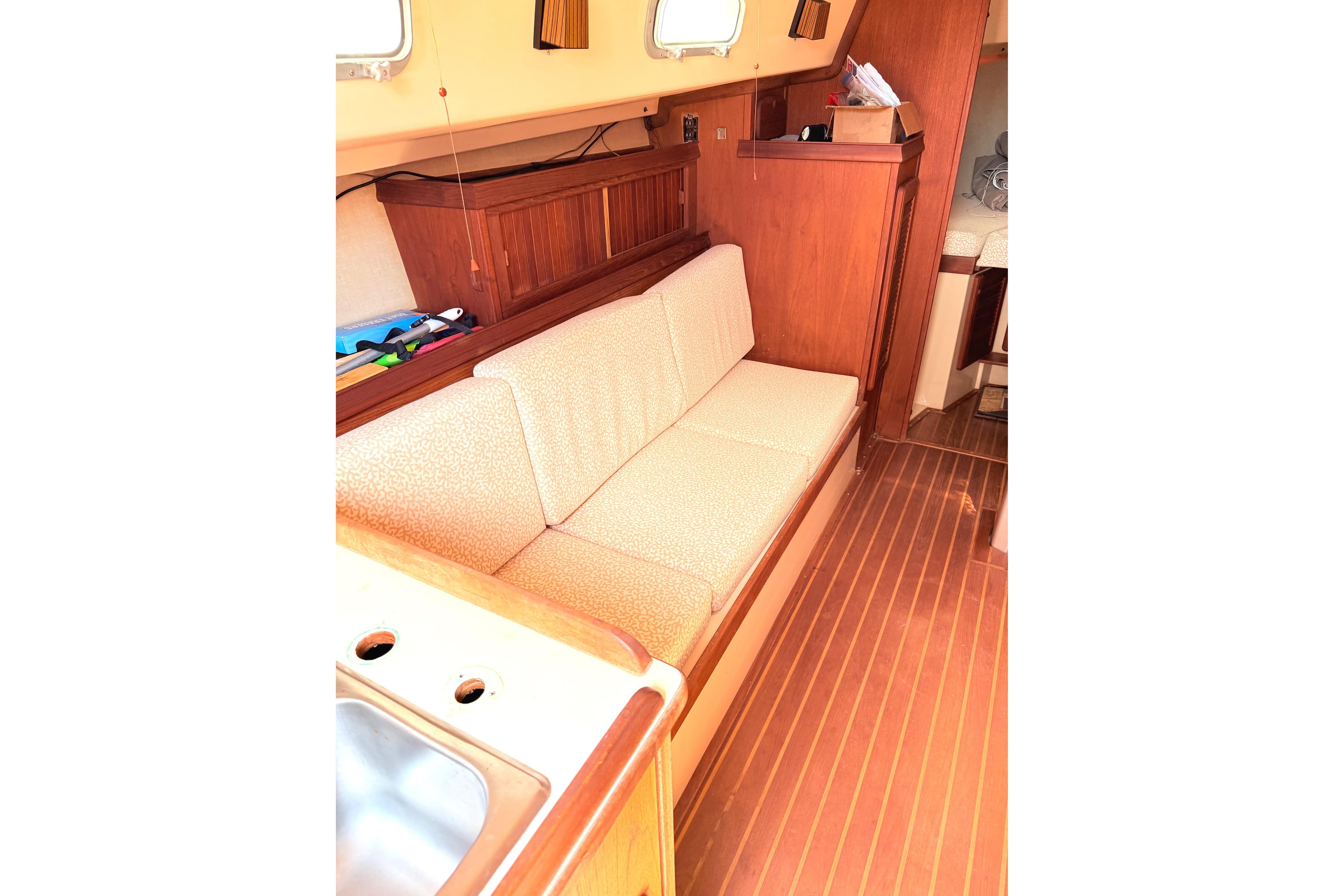 1984 Island Packet boat interior with wooden flooring and cushioned seating.