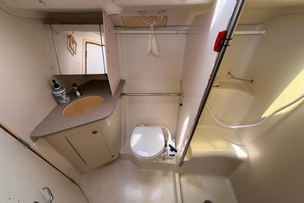 Compact bathroom in a 2002 Hunter 410 yacht, featuring a sink, toilet, and shower.
