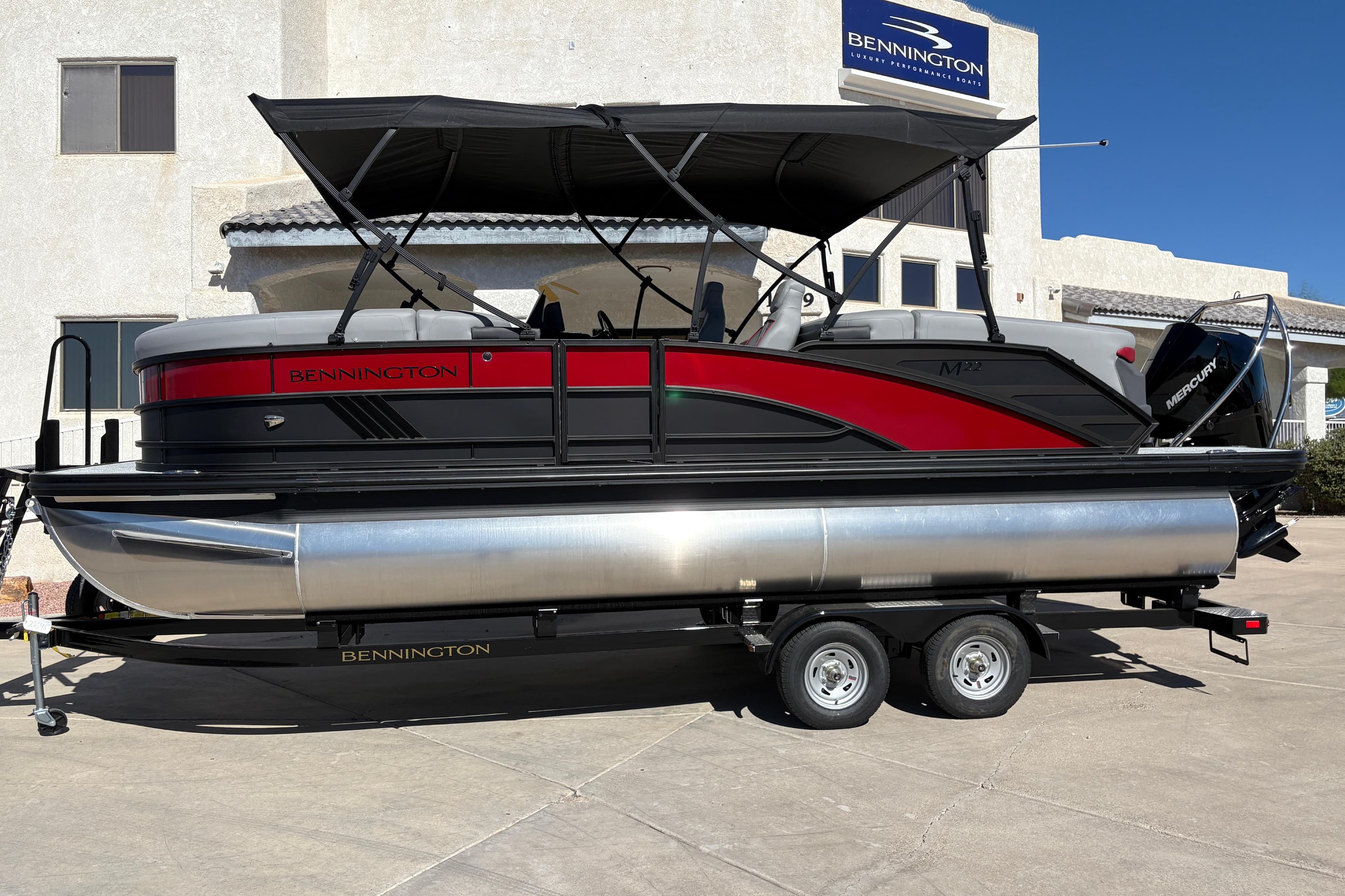 2026 Bennington 22 MFB pontoon boat on trailer, black and red design, parked outdoors.