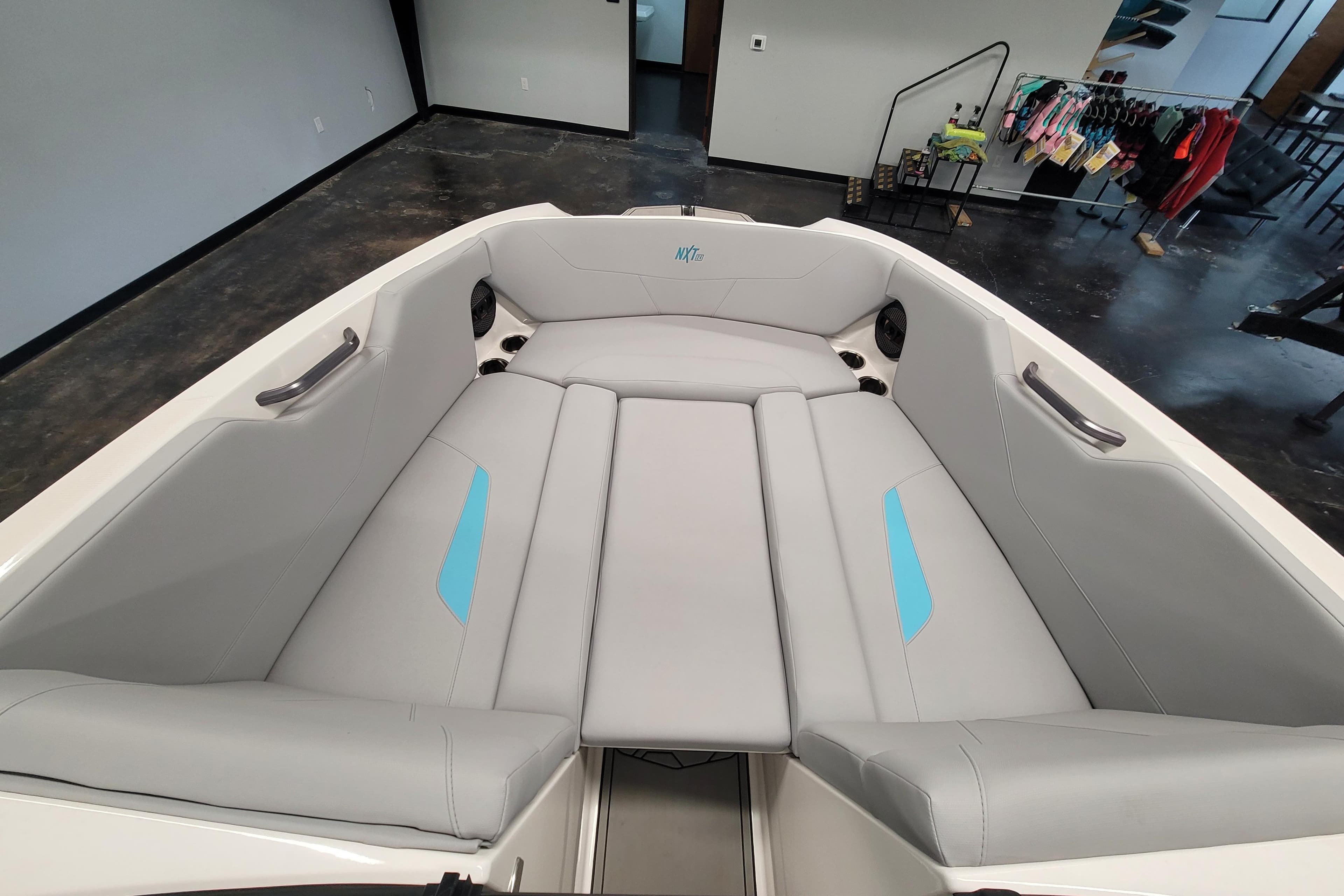 2024 MasterCraft NXT24 boat interior with gray and blue seating in showroom.