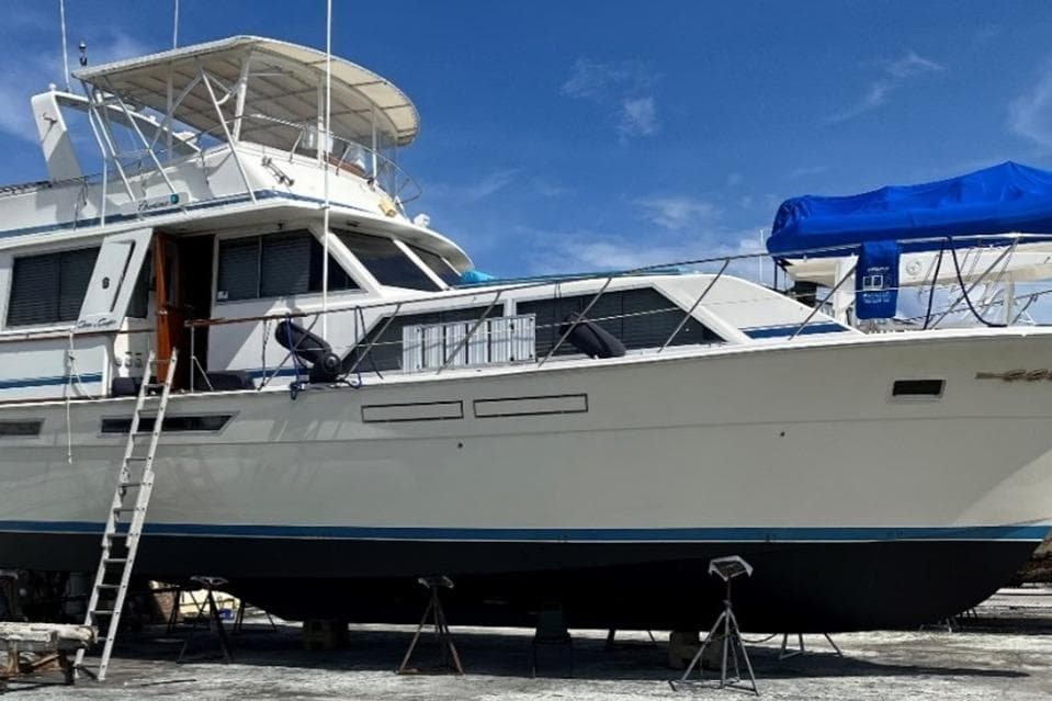 1985 Chris-Craft 500 Constellation yacht on dry dock under clear blue sky.