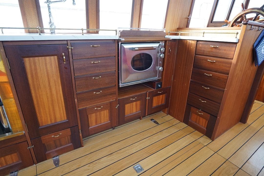 Wooden boat kitchen with custom cabinetry and built-in oven, 2020 design.