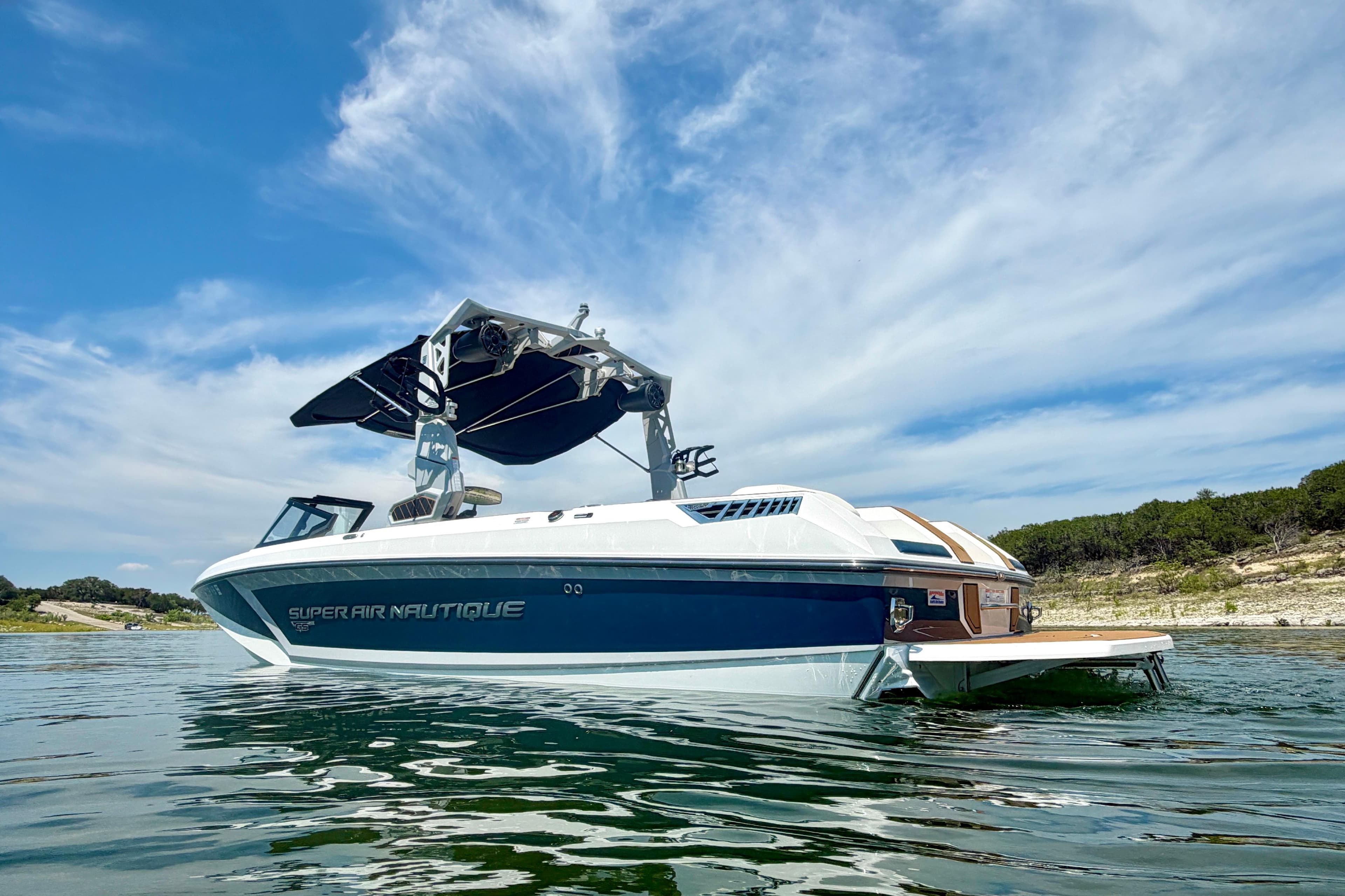 2022 Nautique Super Air Nautique GS24 boat on calm water under a blue sky.