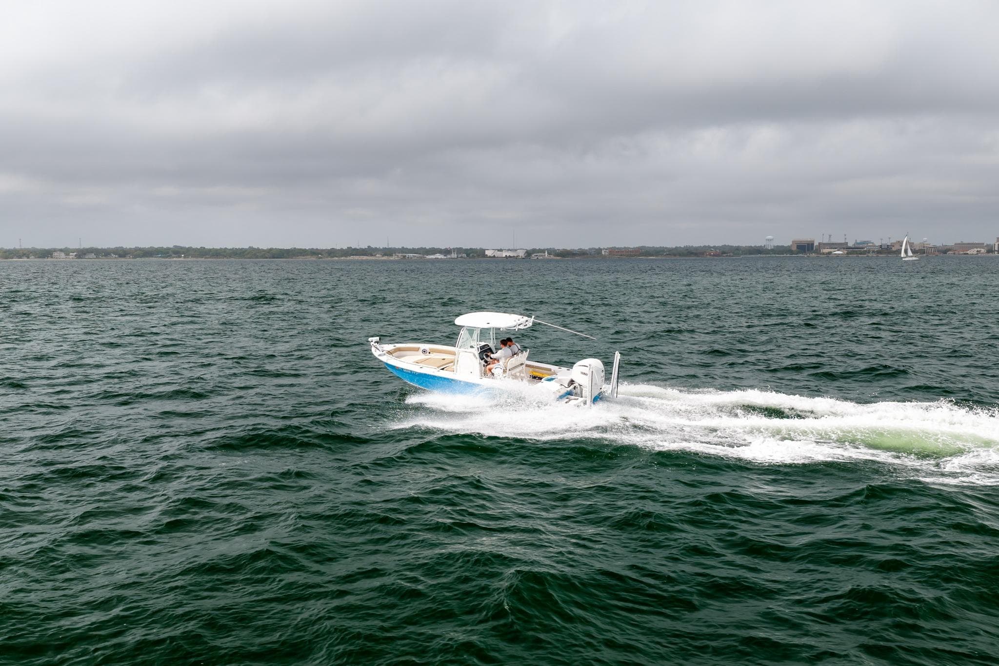 2023 Everglades 243 Center Console boat cruising on open water under cloudy skies.