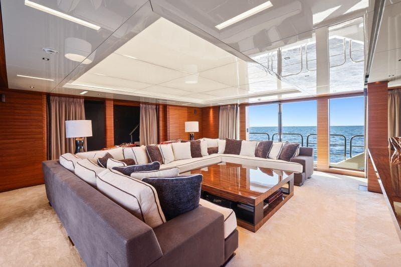 Luxurious yacht interior with large sectional sofa, wooden accents, and ocean view. Elsflether Werft AG, 1986.