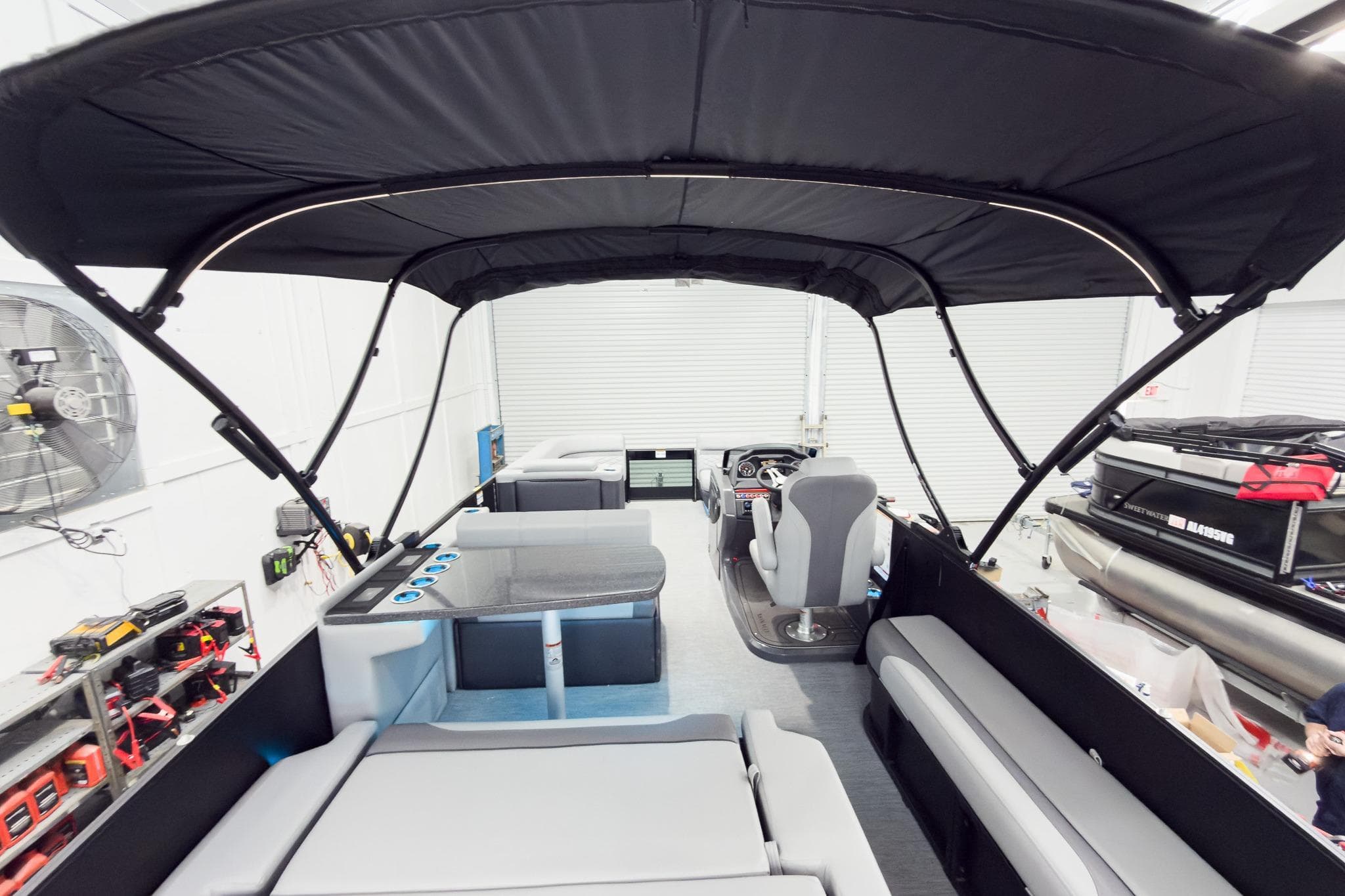 2026 Godfrey Monaco 25' Tritoon with mid-table flip lounge and canopy in showroom.