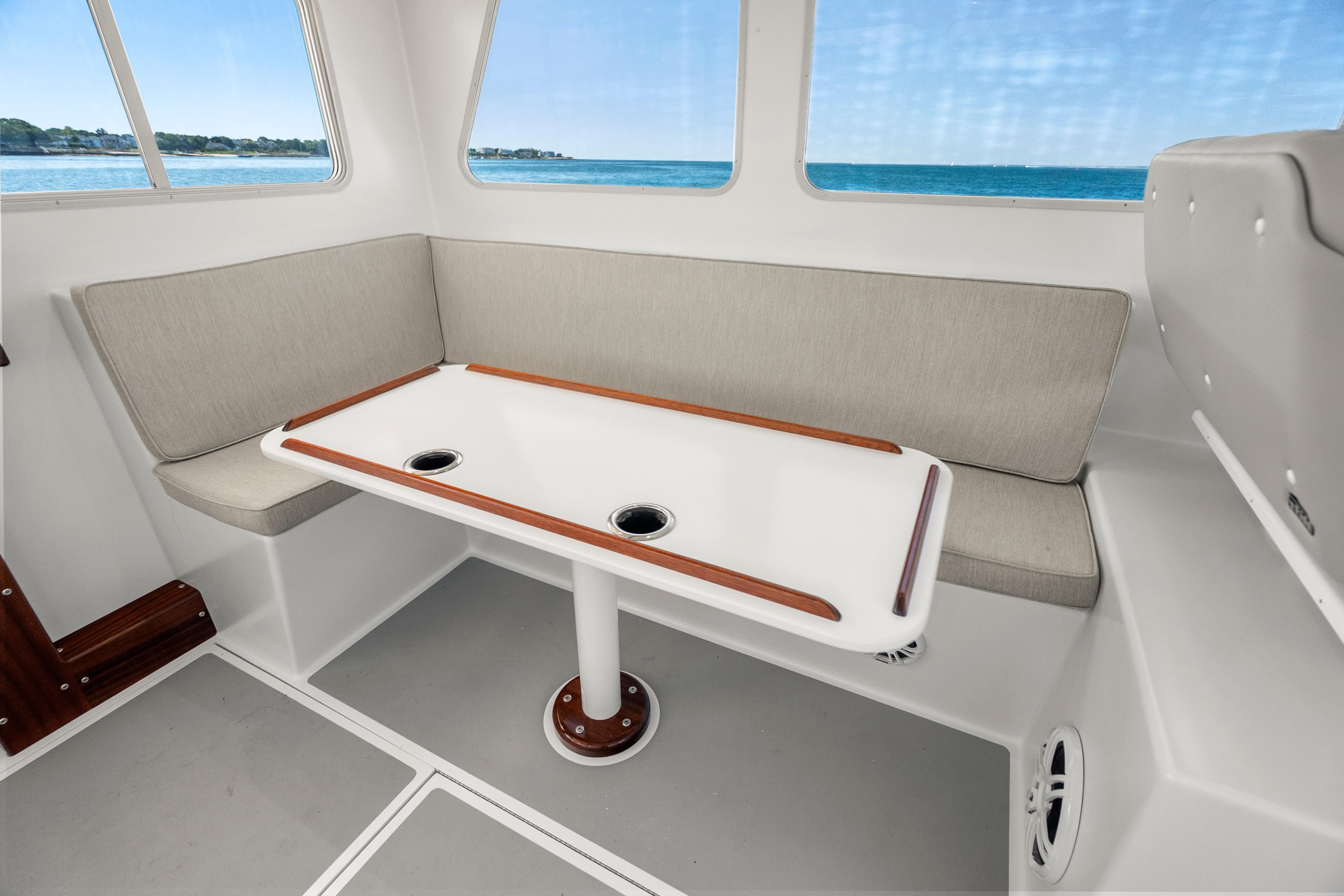 Interior of 2025 Mussel Ridge 42 boat with cushioned seating and table, ocean view.