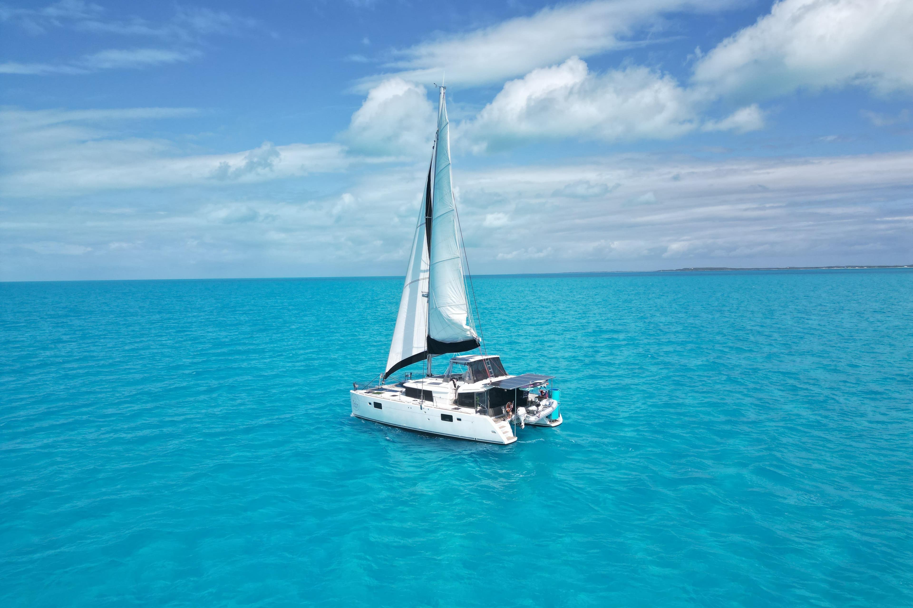 2016 Lagoon 450 F catamaran sailing on clear turquoise waters under a blue sky.