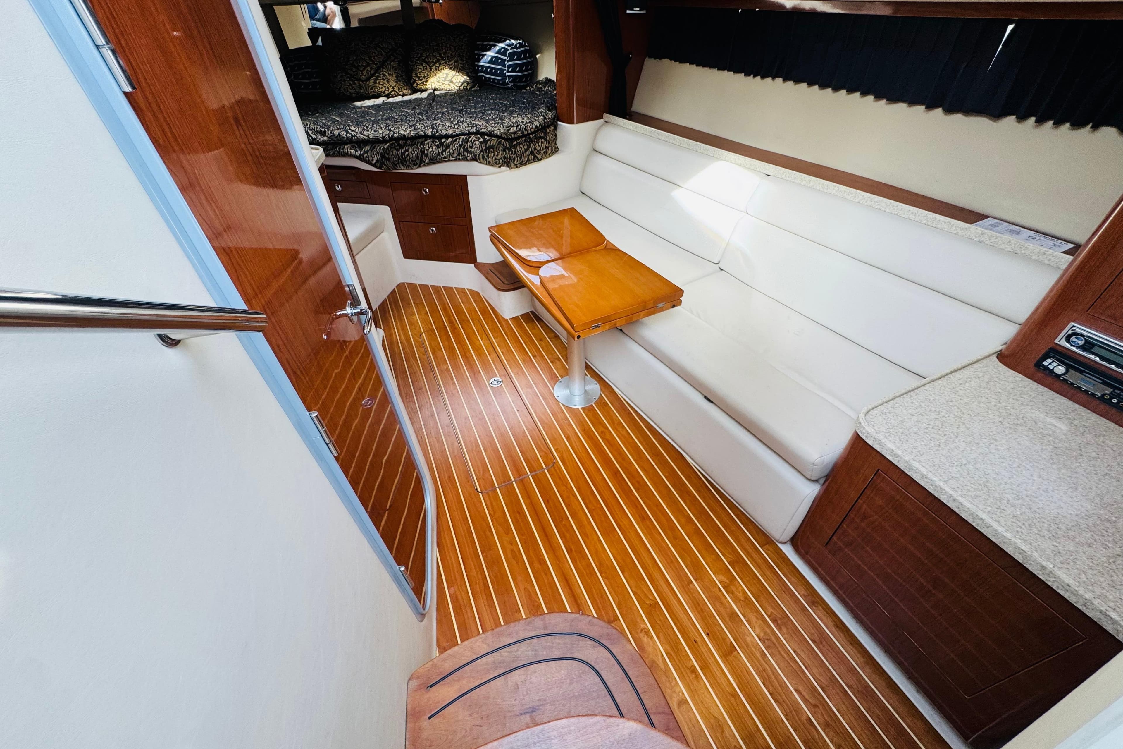 2006 Regal 3360 Window Express interior with wood flooring, white seating, and compact table.