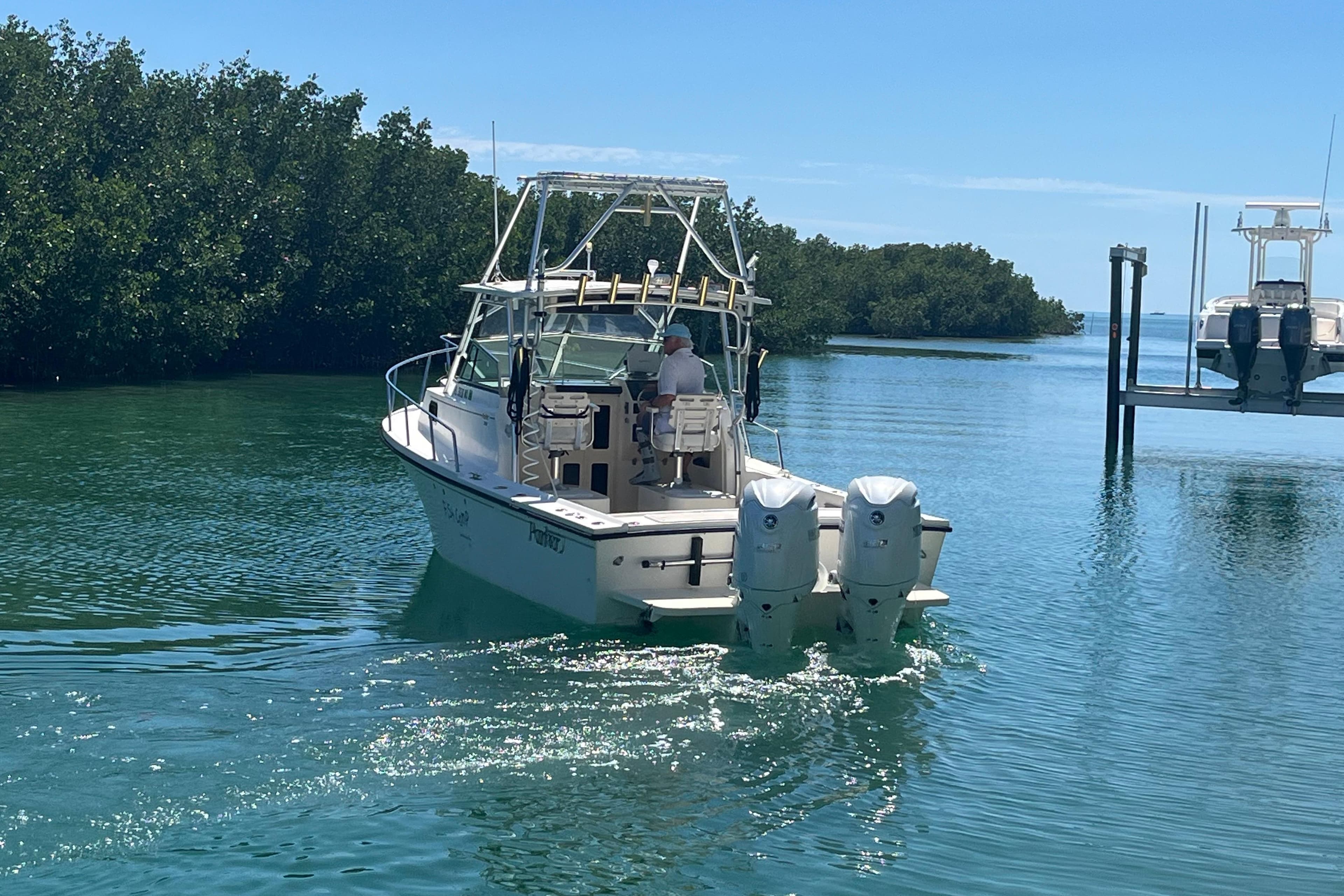 2005 Parker 2510 Modified Vee Walkaround boat cruising in clear waters near mangroves.