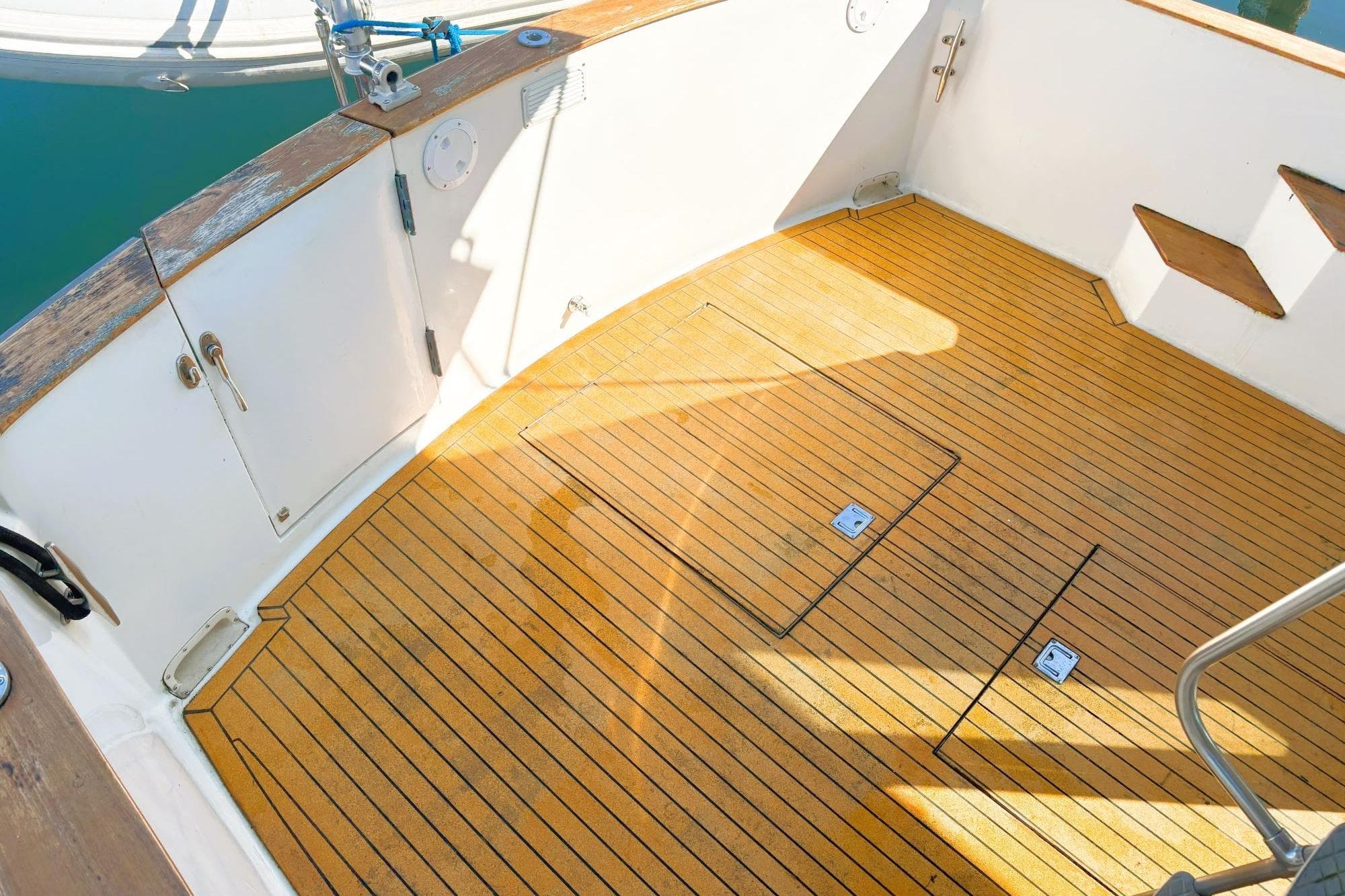 1980 Tollycraft 34 Sedan boat deck with teak flooring and white railings.
