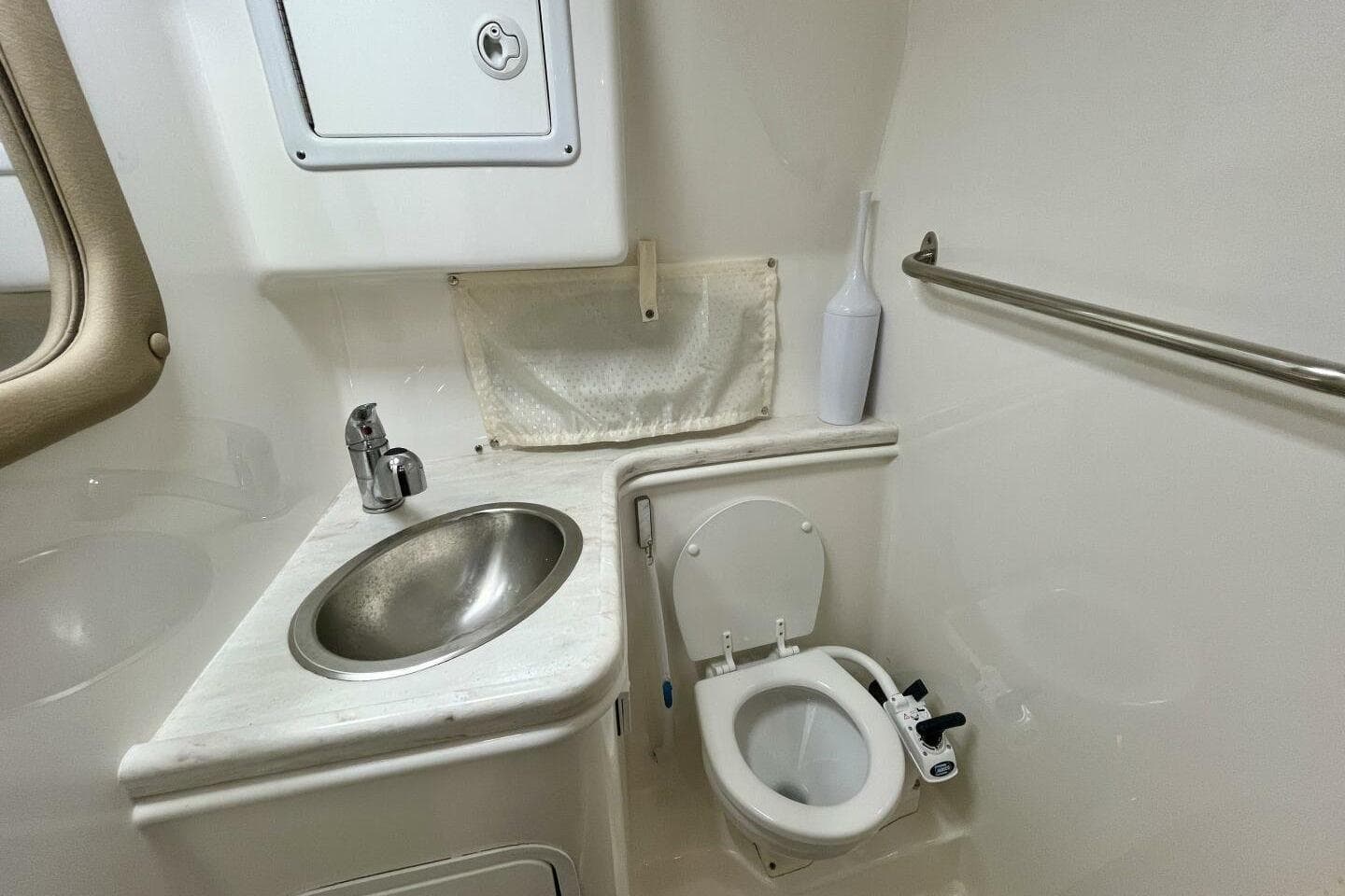2014 Rinker 290 Express Cruiser bathroom with sink, toilet, and storage.