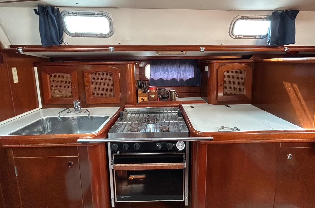 Galley kitchen in 1997 Beneteau Oceanis 50 sailboat with wood cabinetry and stainless steel appliances.