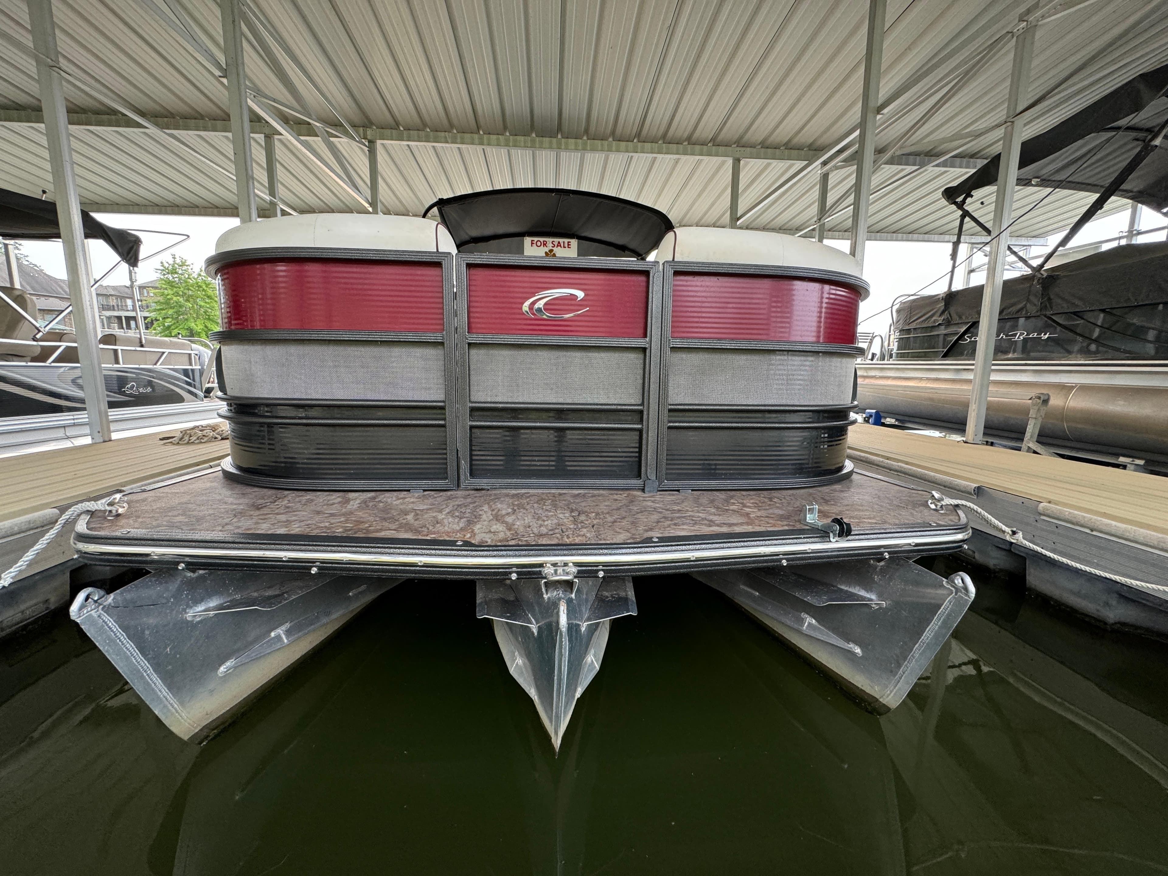 2019 Crest Caribbean 250 SLRC pontoon boat docked under a covered marina.