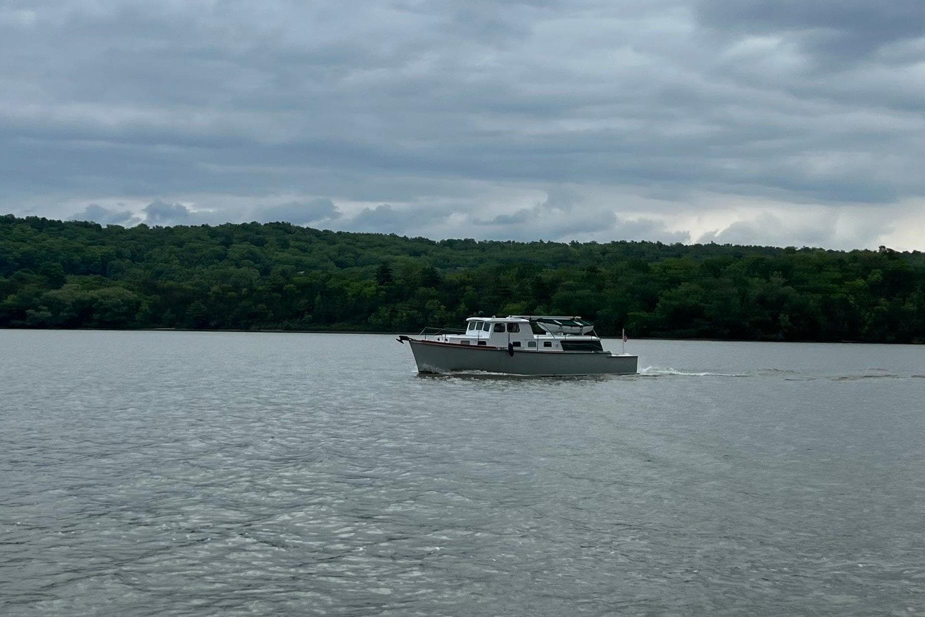 1963 Wiley Trawler cruising on a calm lake with forested shoreline.