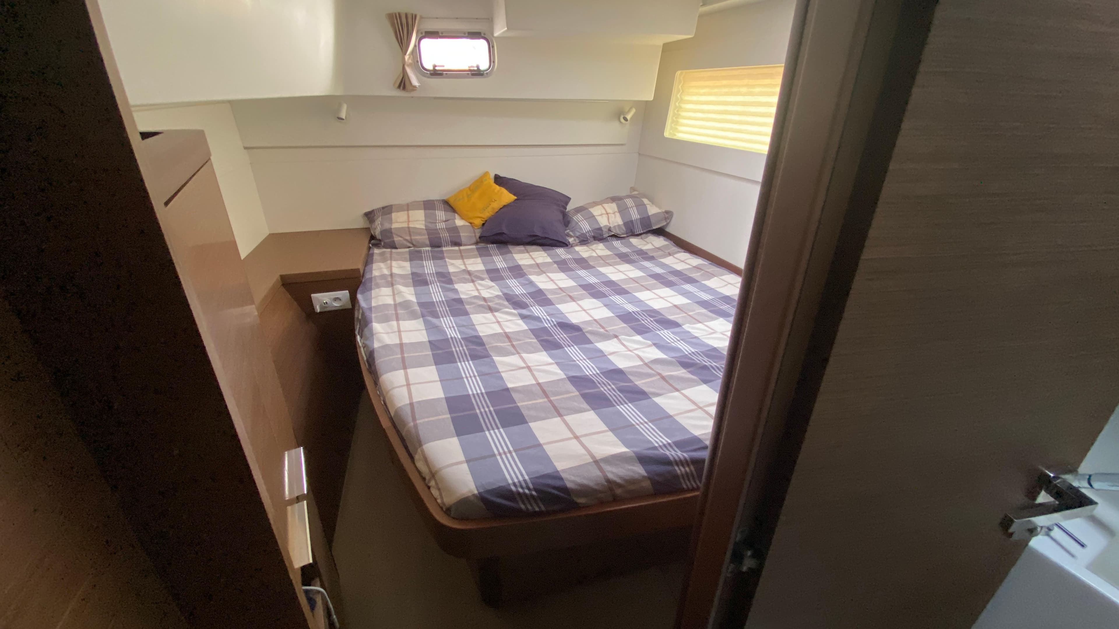 Cozy bedroom in 2019 Lagoon 40 yacht with plaid bedding and natural light.