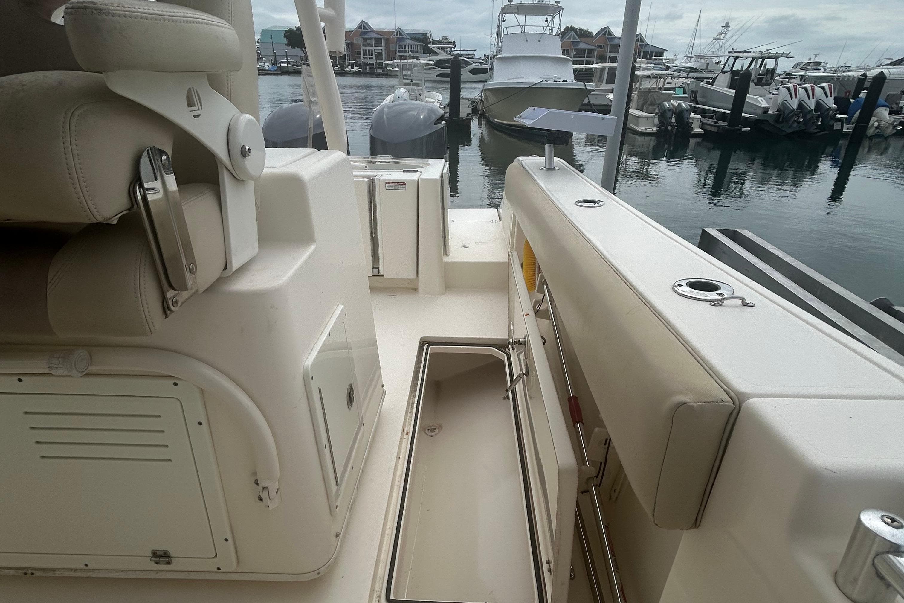 2016 Cobia 296 Center Console boat interior at marina, featuring seating and storage compartments.