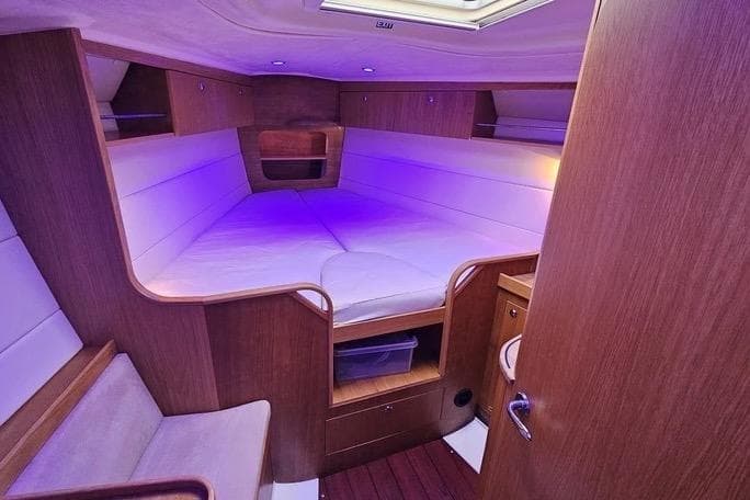 Cozy cabin interior of 2010 Maxi 1300 sailboat with ambient lighting and wooden finish.