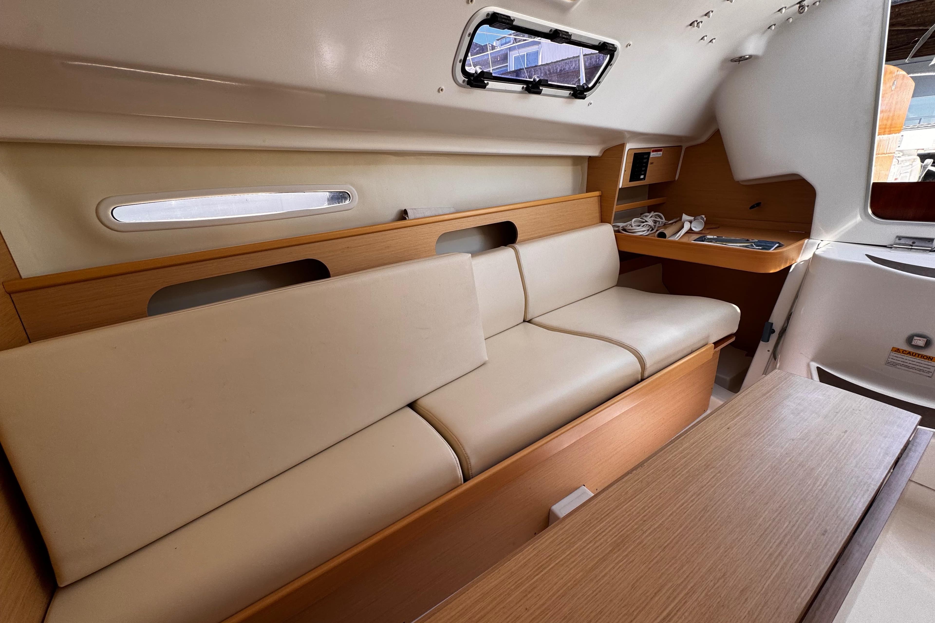 Interior of 2014 Beneteau FIRST 25 S sailboat with beige seating and wooden accents.
