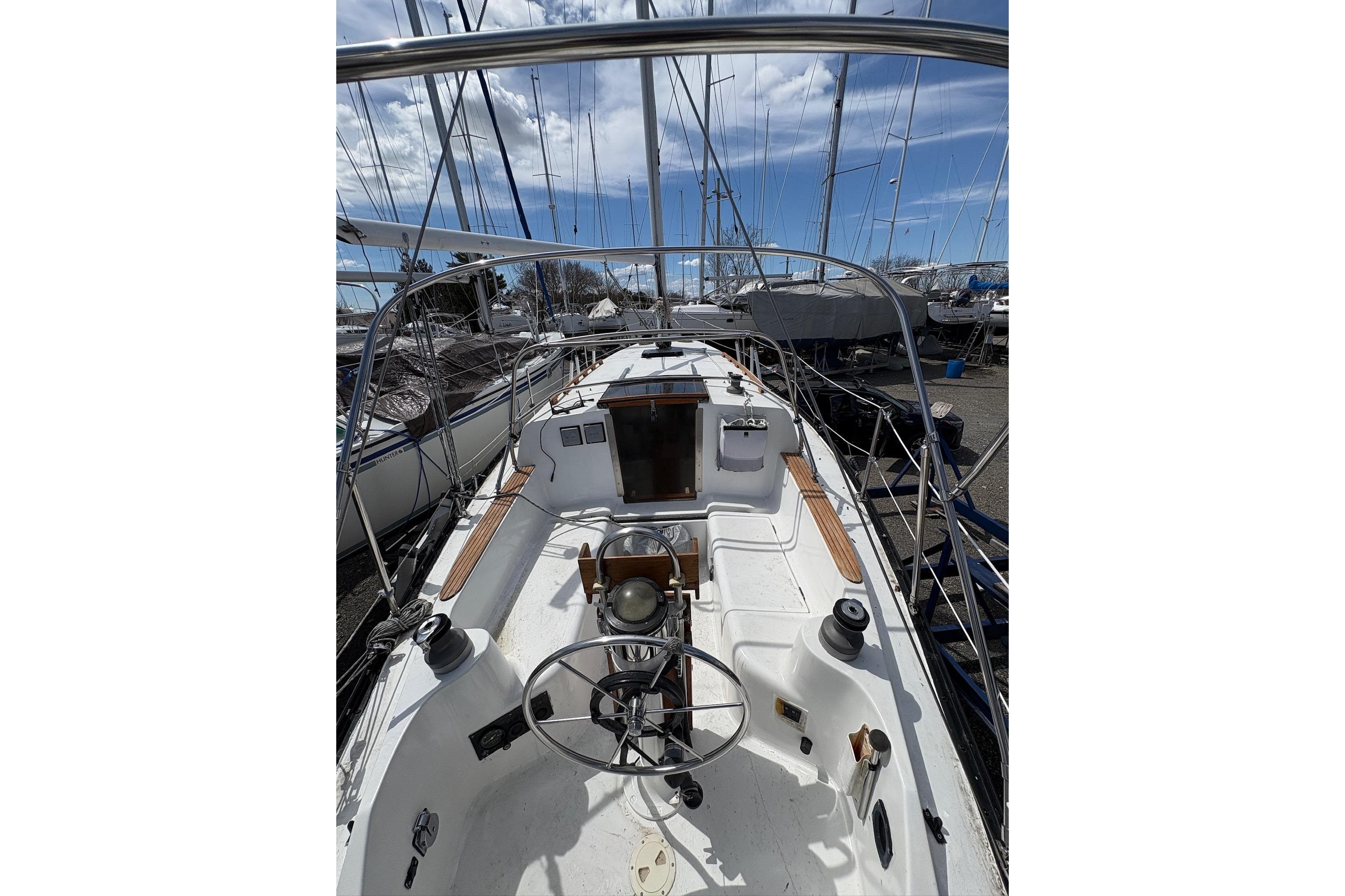 1984 Hunter 34 sailboat cockpit with steering wheel, docked under a clear blue sky.