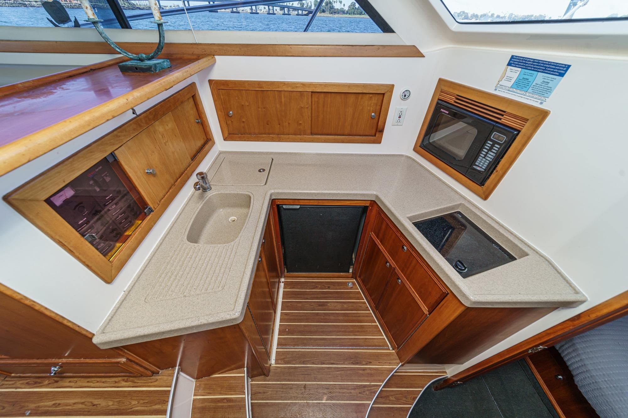 2006 Riviera 33 Flybridge yacht kitchen with sink, microwave, and wooden cabinetry.