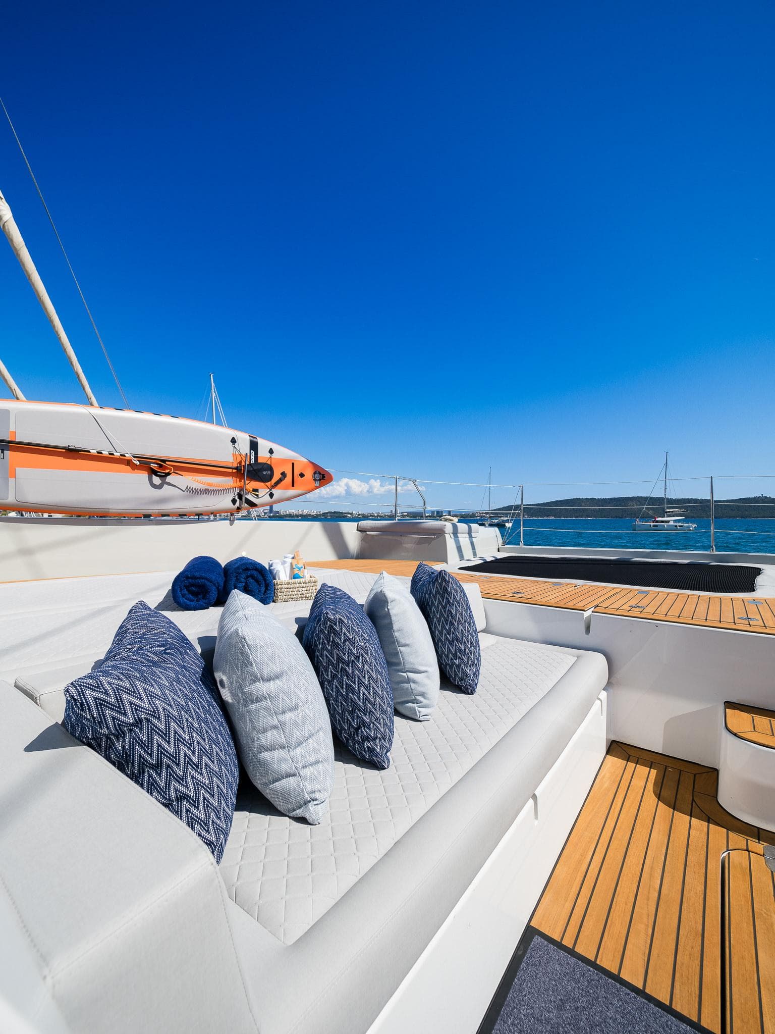 Luxurious Sunreef 70 Eco yacht deck with cushions, 2024 model, under clear blue sky.