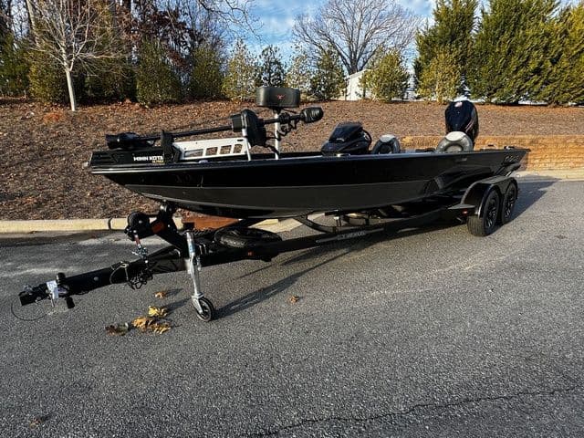 2024 Vexus AVX2080 boat on trailer, parked outdoors, surrounded by trees.