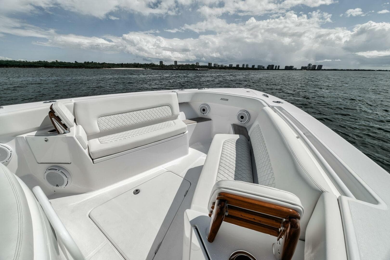 2023 Jupiter 40 boat interior with white seating, on a calm sea under a cloudy sky.