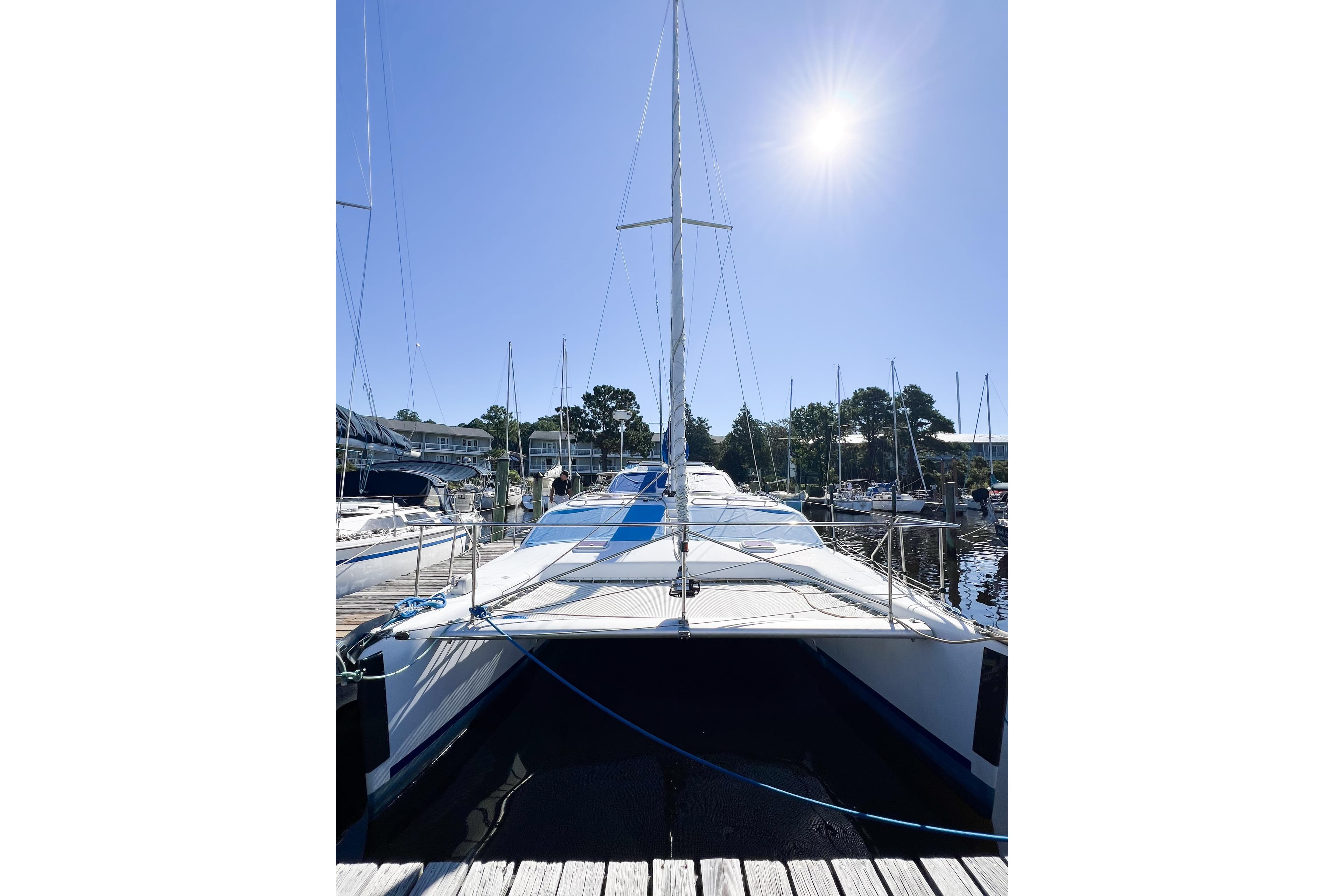 Sailboat TomCat 9.70 s, 2012 model, docked under clear blue sky.