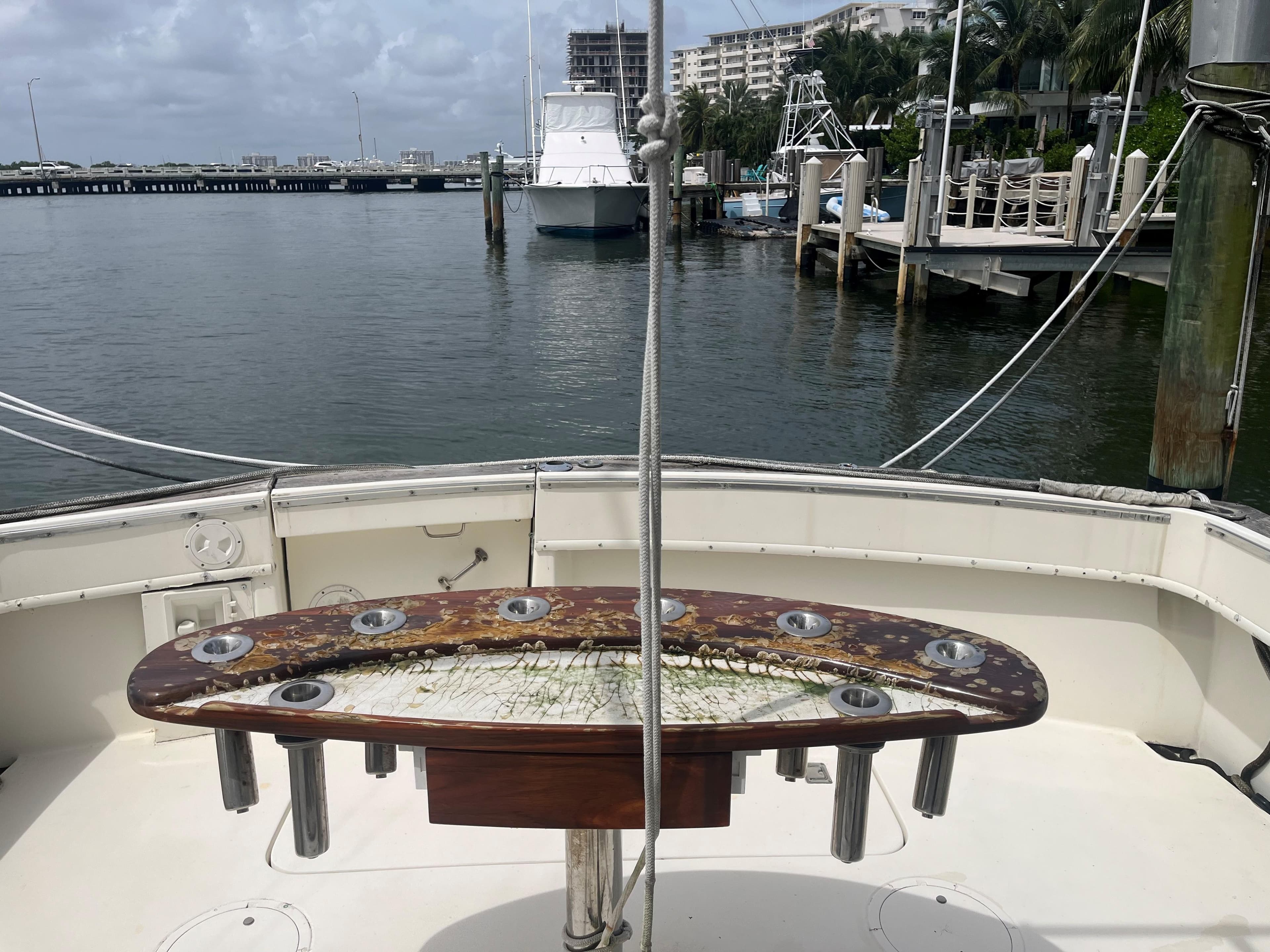 1985 Hatteras 45 Convertible yacht docked at marina, featuring fishing rod holders.