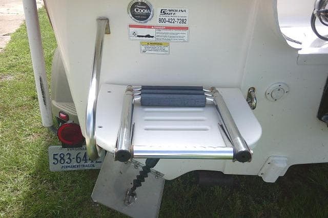 2013 Carolina Skiff 198 DLV boat ladder and platform, featuring safety stickers and trailer license plate.
