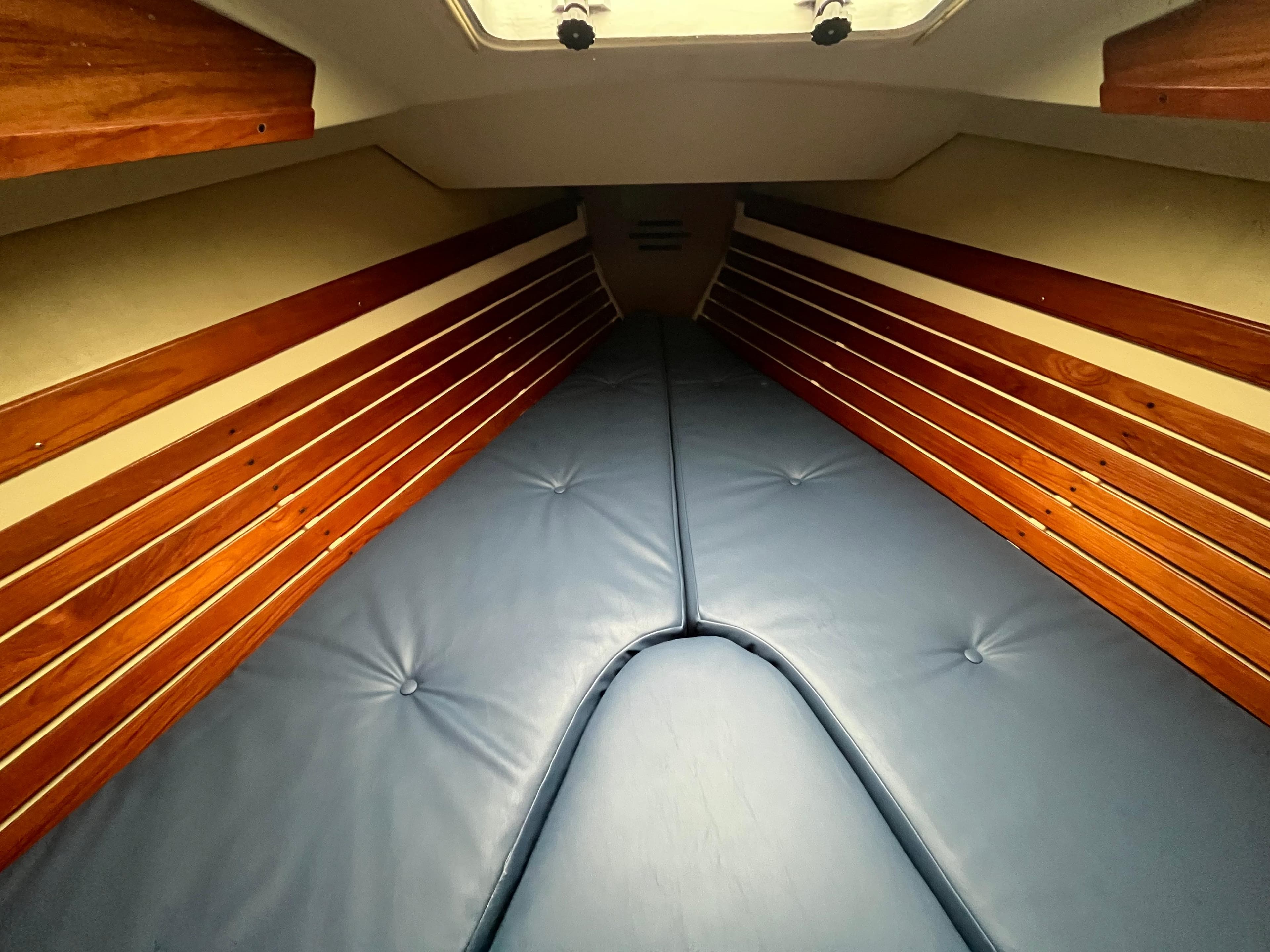 Interior cabin of 1986 Pearson 33-2 sailboat with blue cushions and wooden paneling.