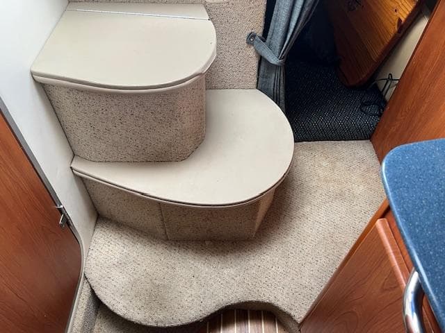 Interior steps of a 2006 Bayliner 275 boat, featuring carpeted flooring and wooden accents.
