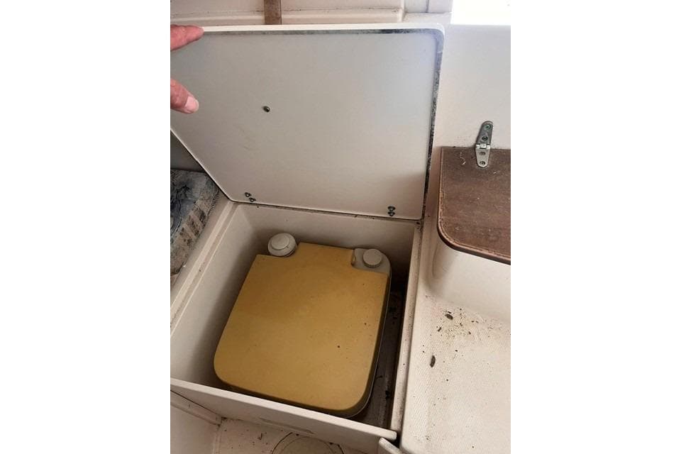 Storage compartment in a 2002 Grady-White Gulfstream 232 boat, featuring a yellow container.