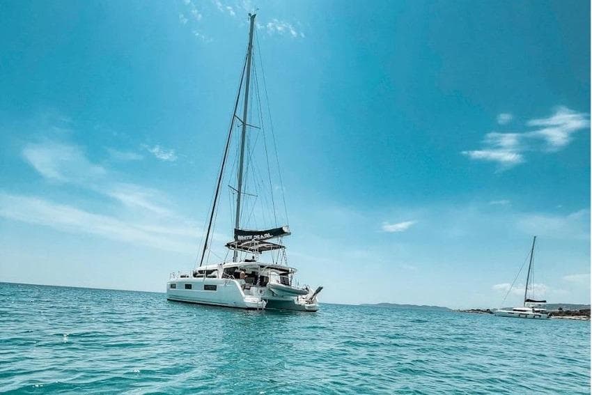 2020 Lagoon 46 catamaran sailing on clear blue waters under a sunny sky.