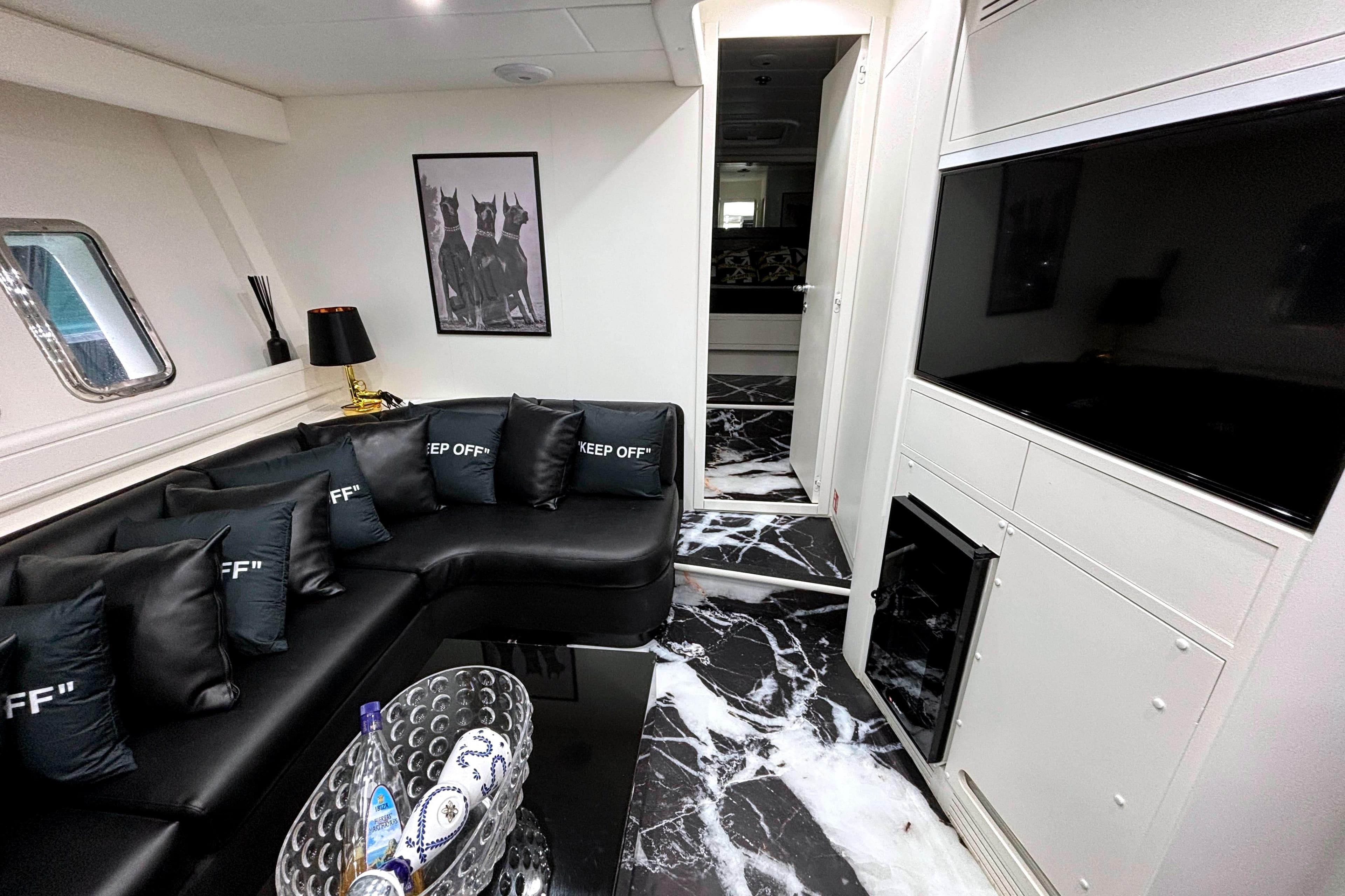 Luxurious interior of 2002 Mangusta 72 yacht with black leather seating and modern decor.